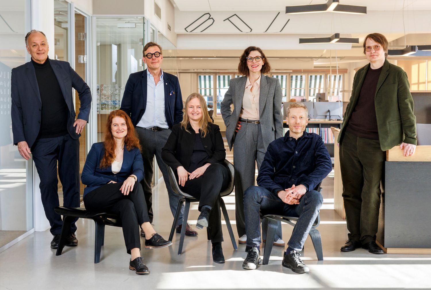 Affärsteam arrangerade i avslappnade poser längs en kontorshall med modern inredning