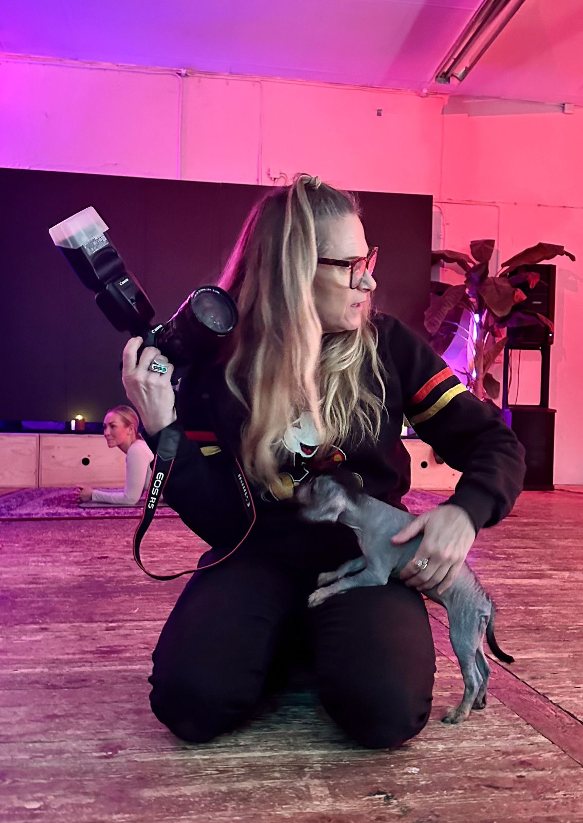 Fotograf sitter på golvet och tar kreativa bilder i en rosa upplyst studio