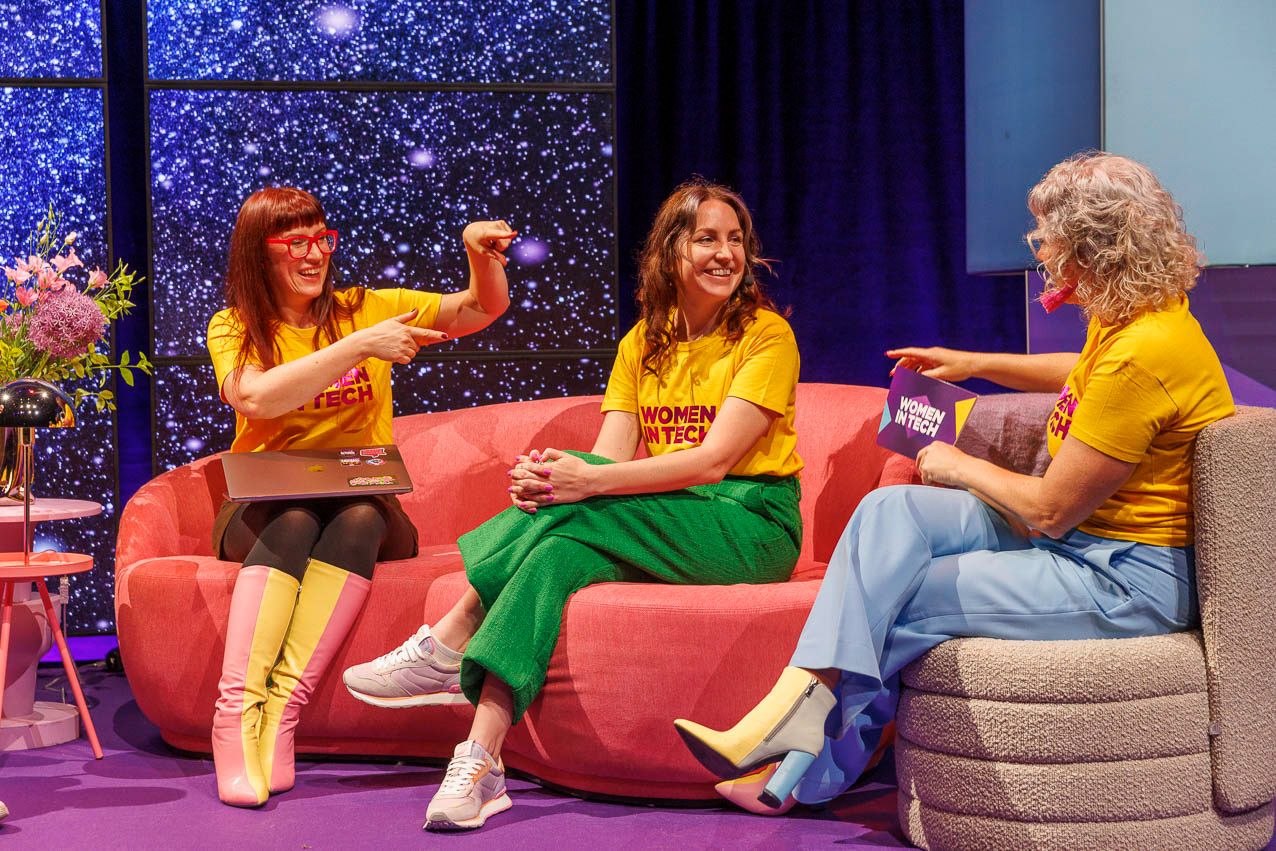 Conference attendees seated on colorful couches during a panel discussion.