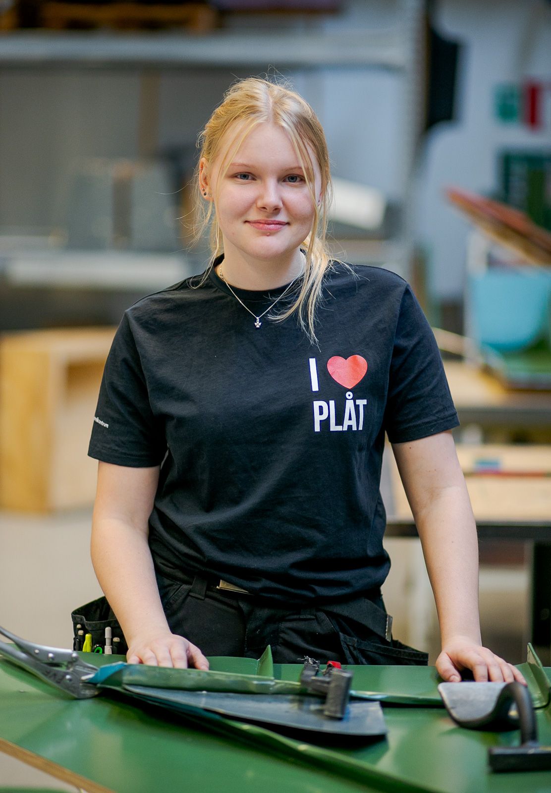Person wearing black t-shirt working at industrial workstation with green surface.