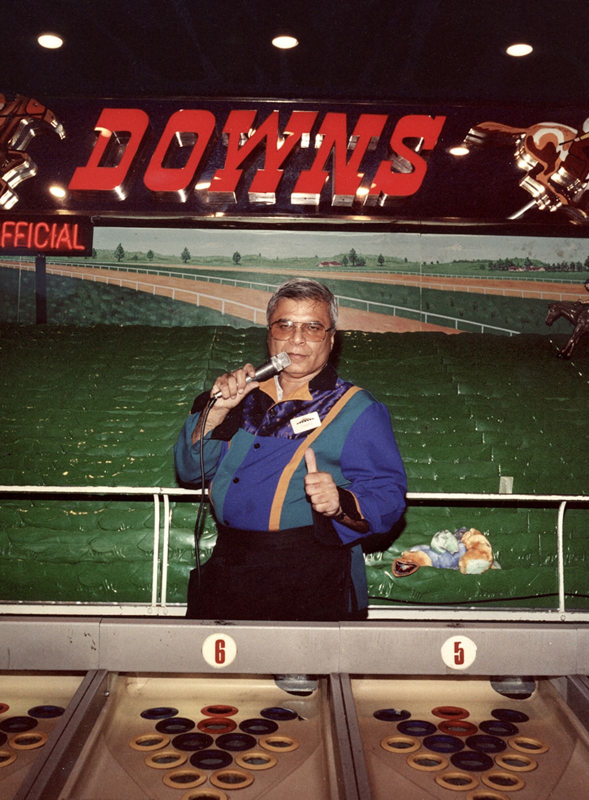 Person in blue uniform operating gaming equipment in an arcade setting.