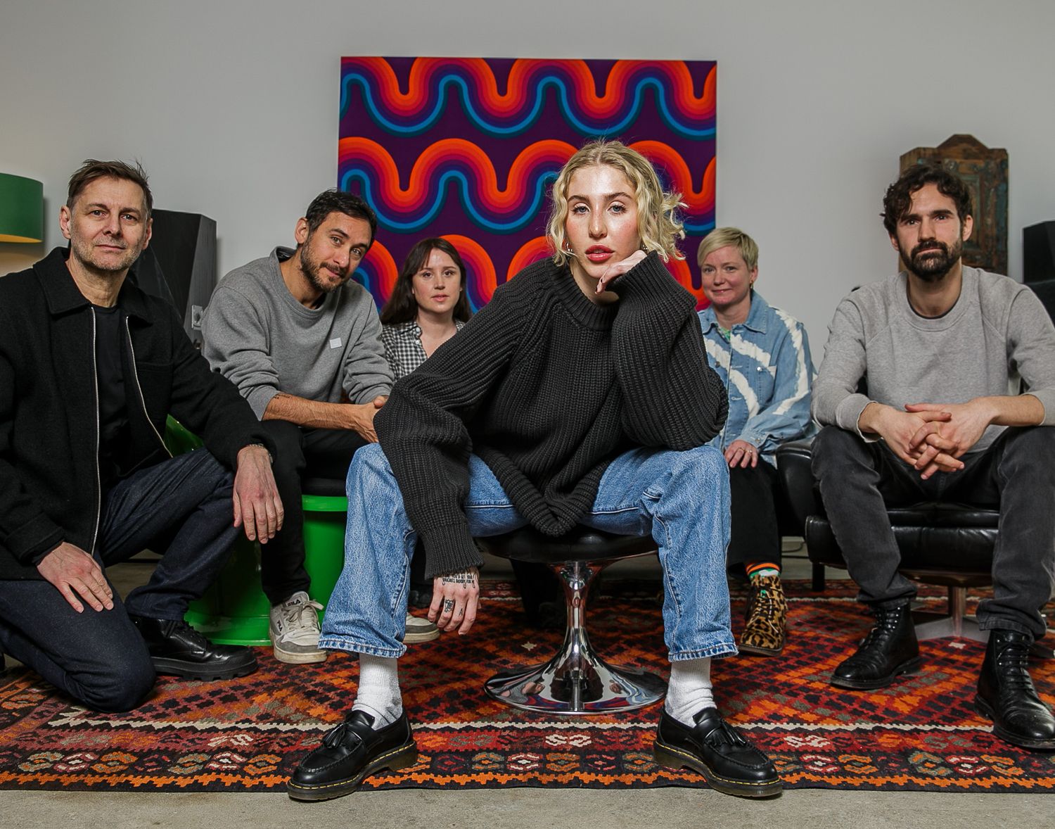 People sitting casually on a patterned carpet in an indoor space.