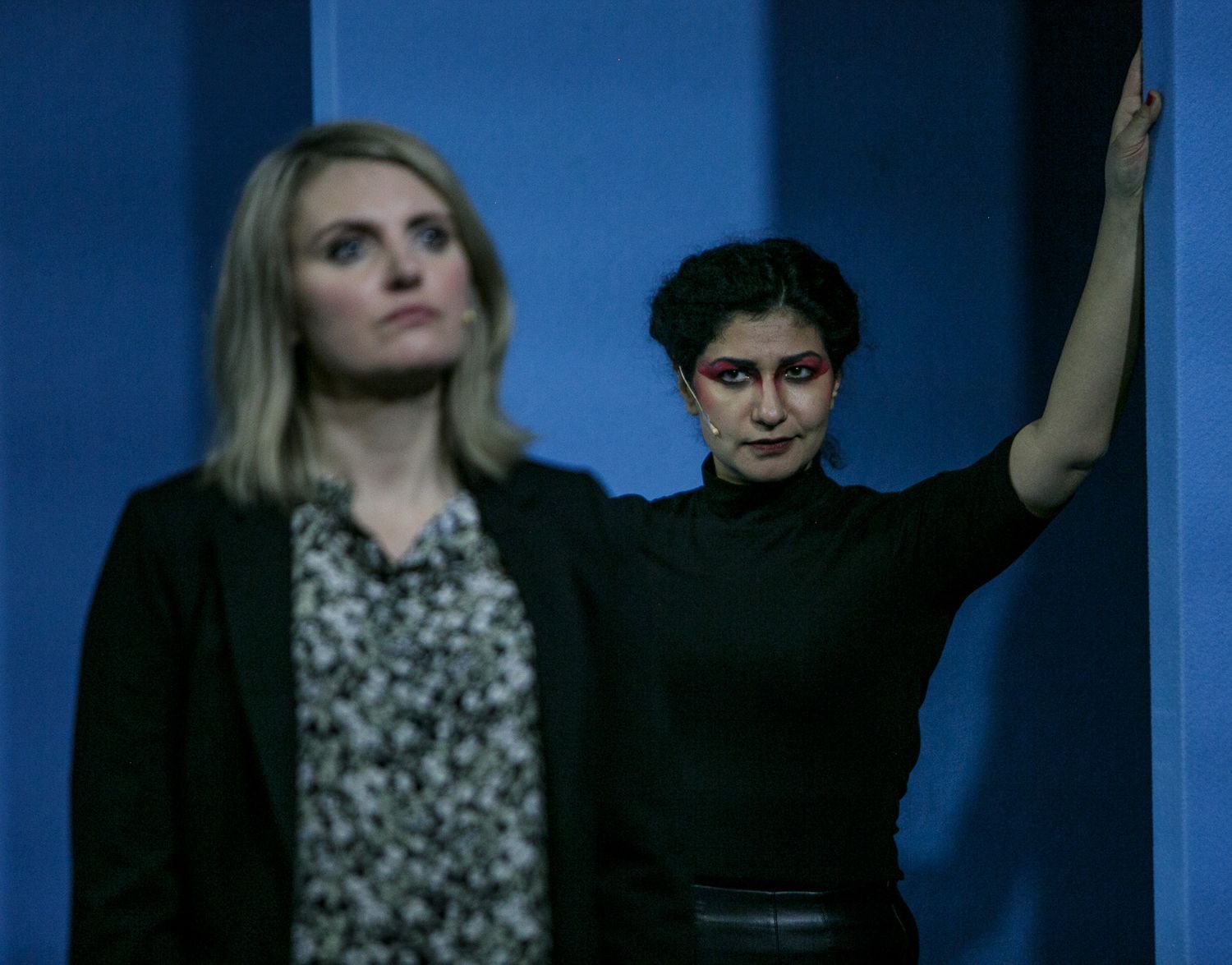 Performers in dramatic poses against a deep blue theatrical backdrop.