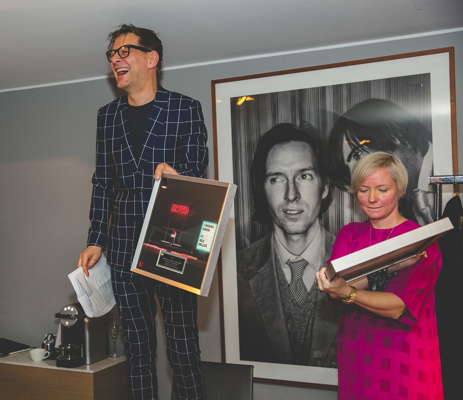 People holding and displaying framed awards at an indoor ceremony.