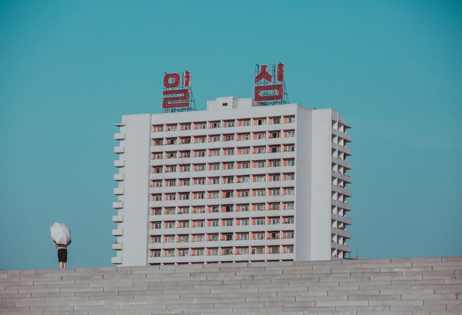 White hotel building with repetitive balconies against a bright blue sky.