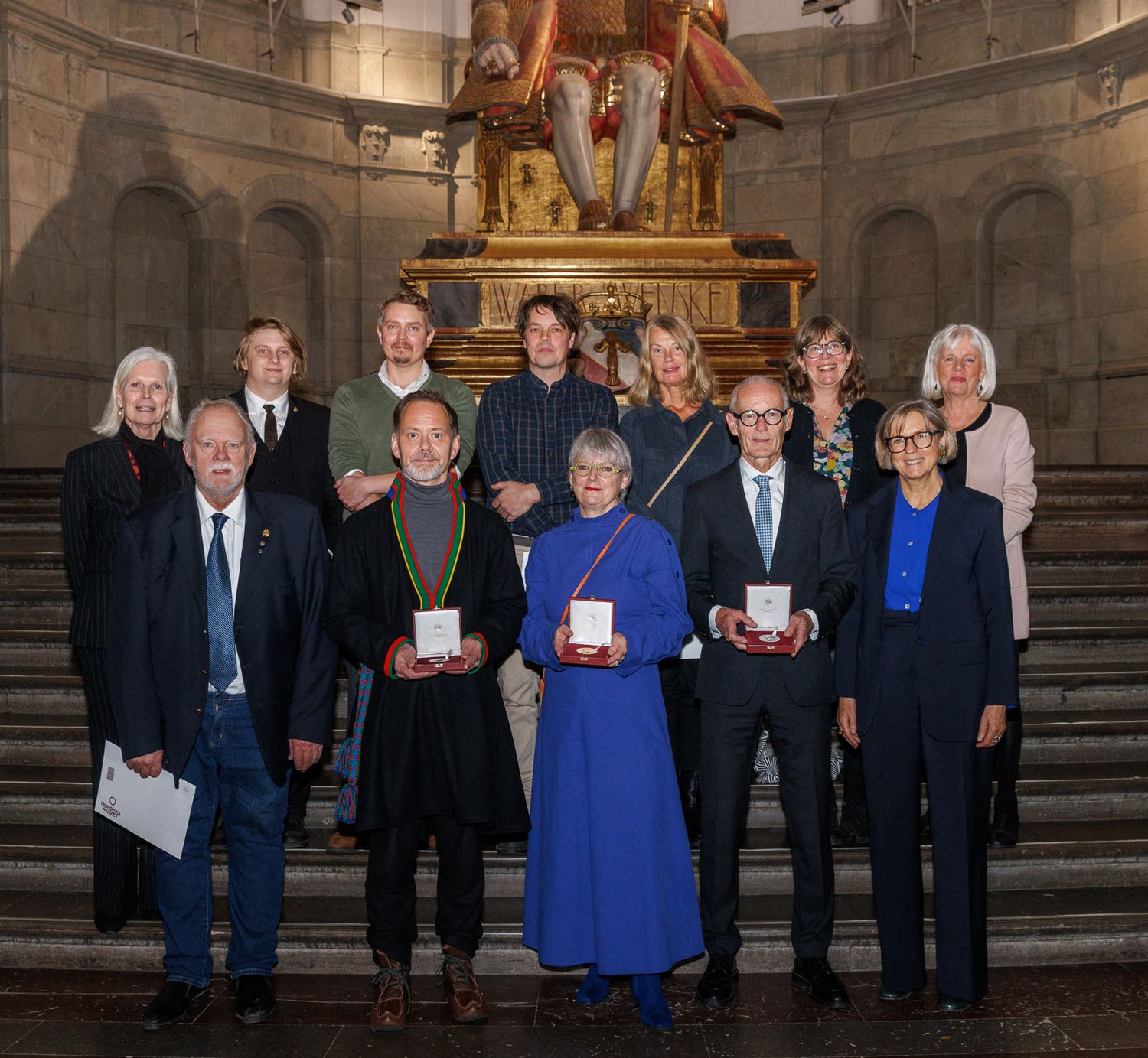 Formal group photo on grand stone steps with decorative altar in background.