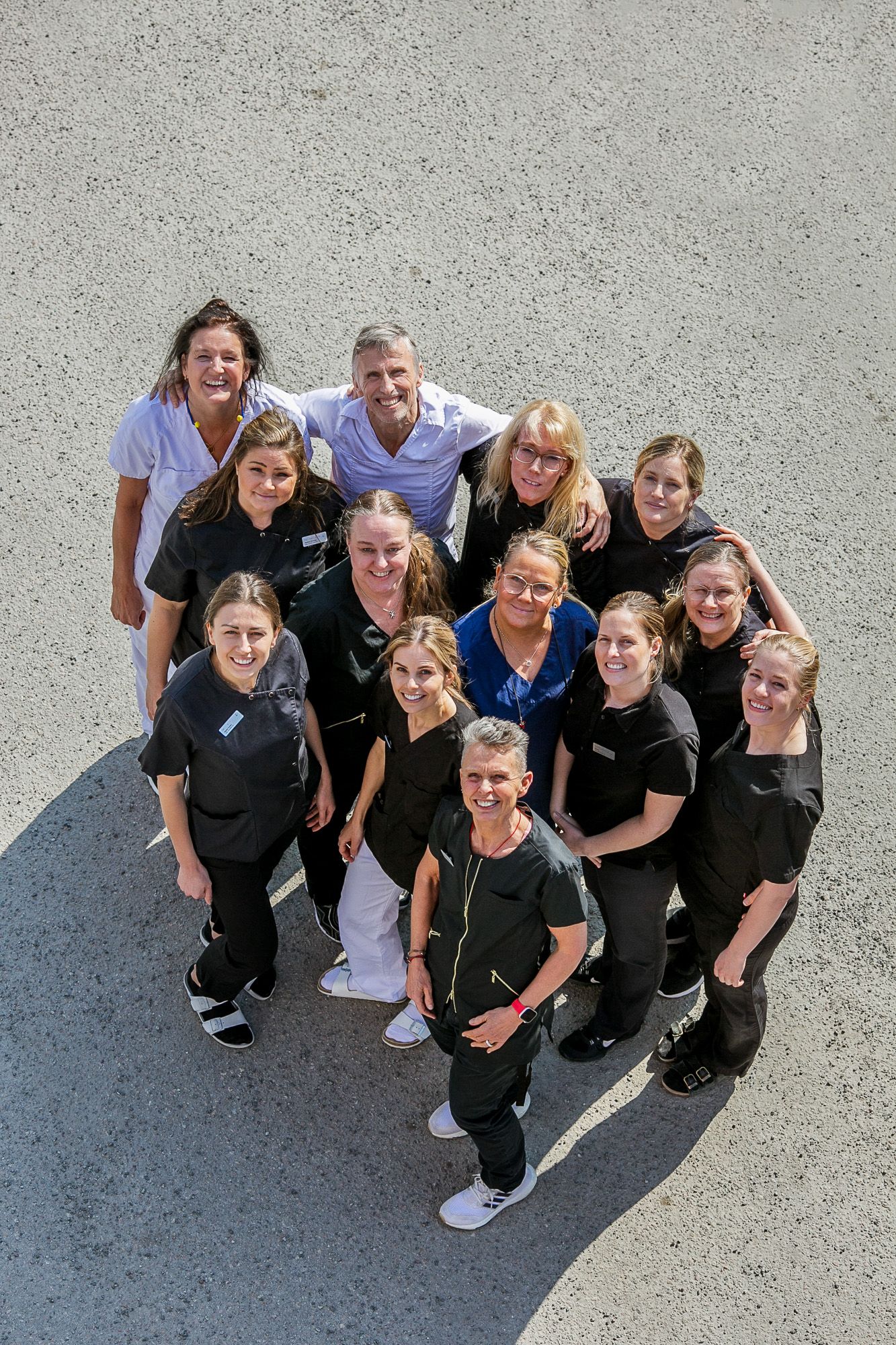 Overhead view of dental office team wearing black and white uniforms posing together in a group formation.