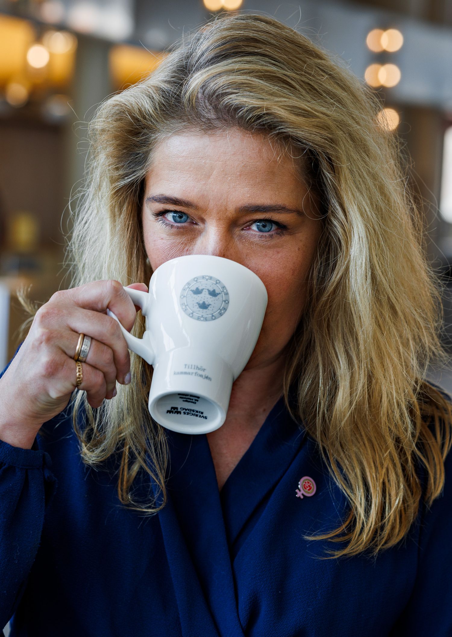 Person in navy blue shirt drinking from white coffee cup.