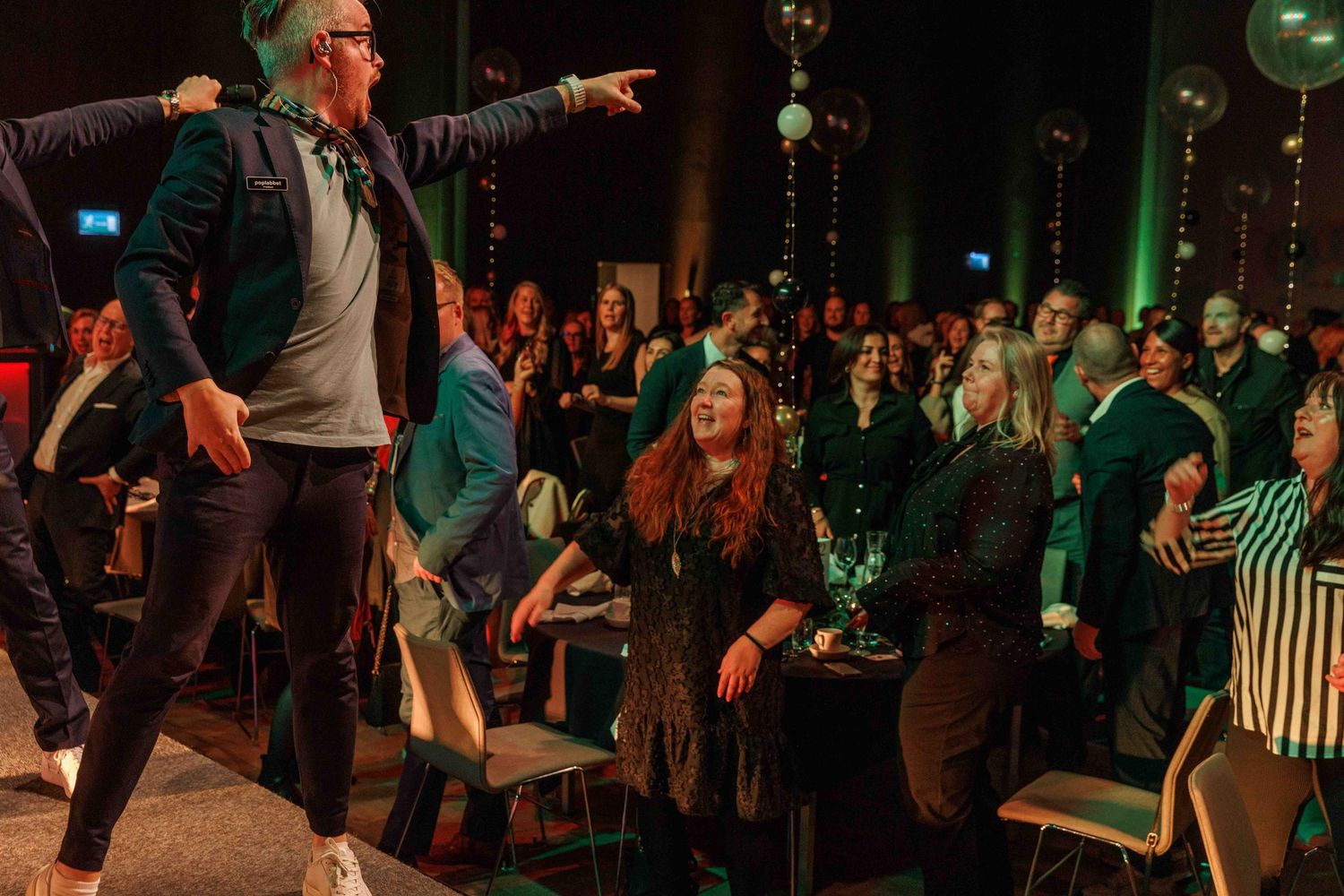 Crowd enjoying entertainment in a dimly lit venue with green ambient lighting.