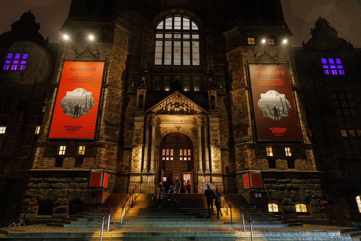 Nighttime exterior view of a gothic-style building with illuminated windows.