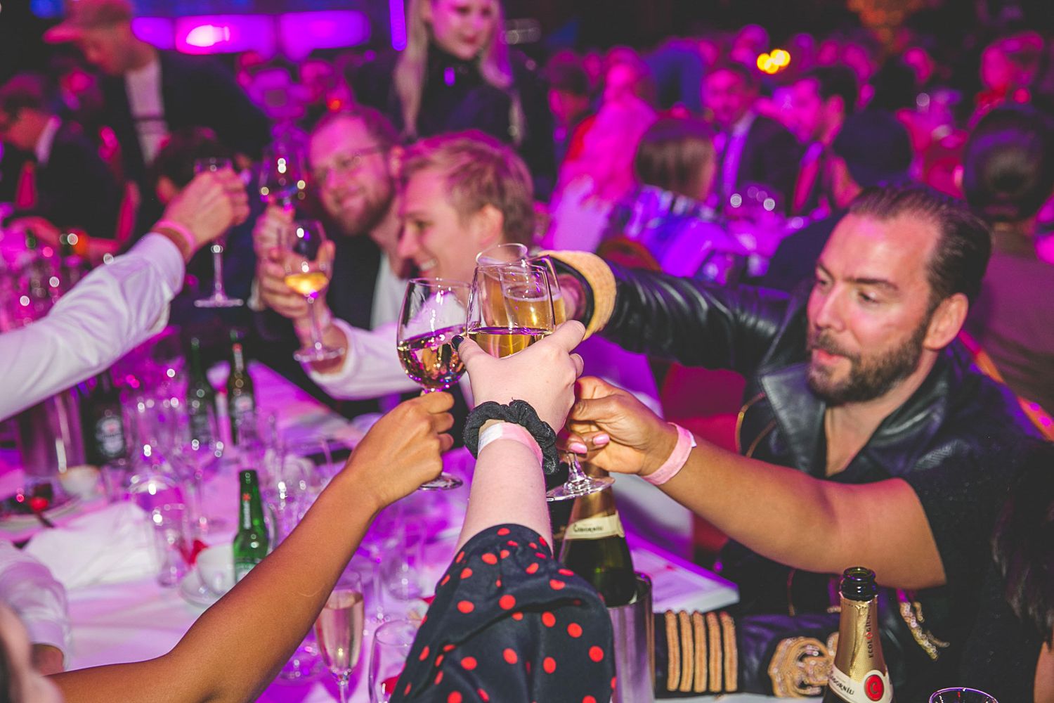 Celebration scene with pink and purple lighting at formal event.