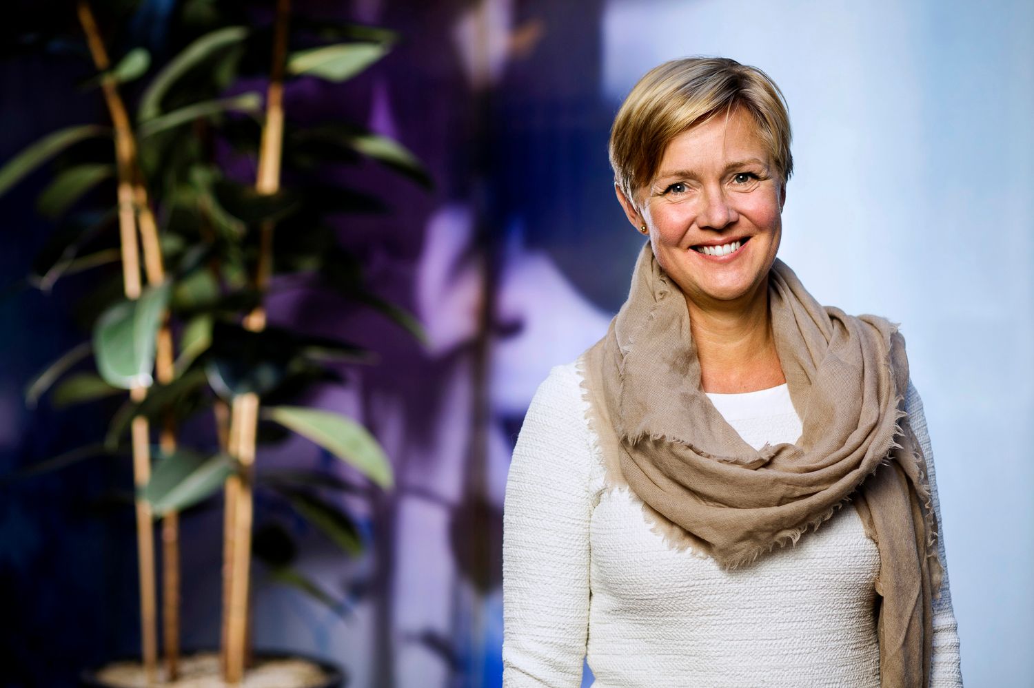 Professionellt porträtt av en person i affärsklädsel som ler varmt mot en suddig bakgrund