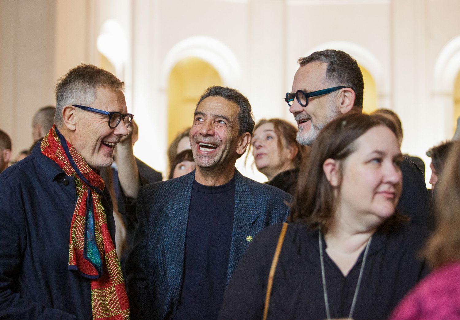 Group of people having animated conversations and laughing together in a casual setting.