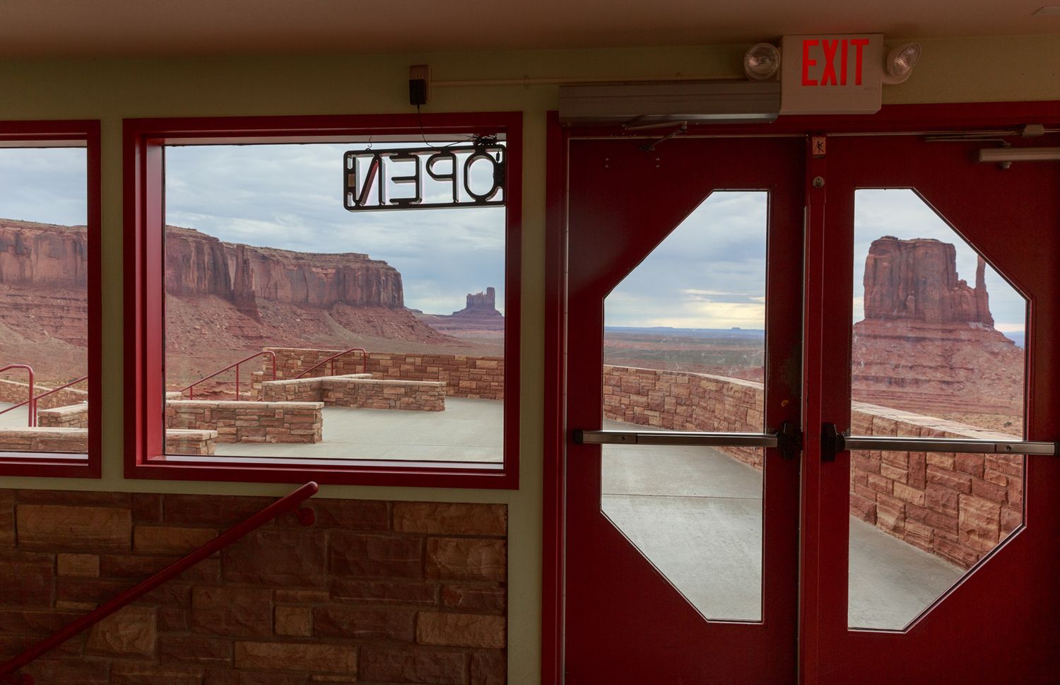 Interior view of a room with red-tinted windows overlooking a desert canyon landscape.