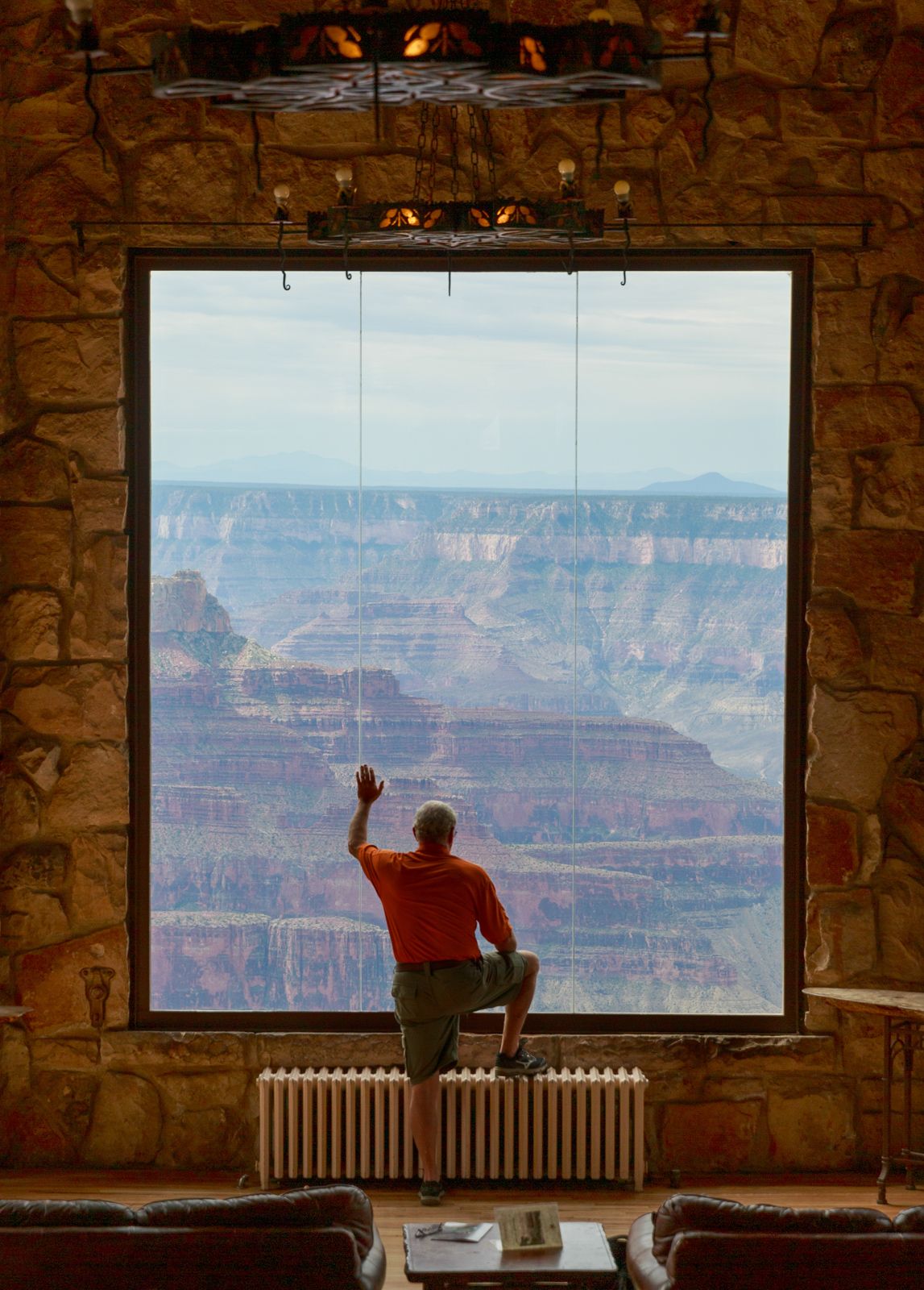 Silhouette of person at Grand Canyon viewing window framed by stone architecture.