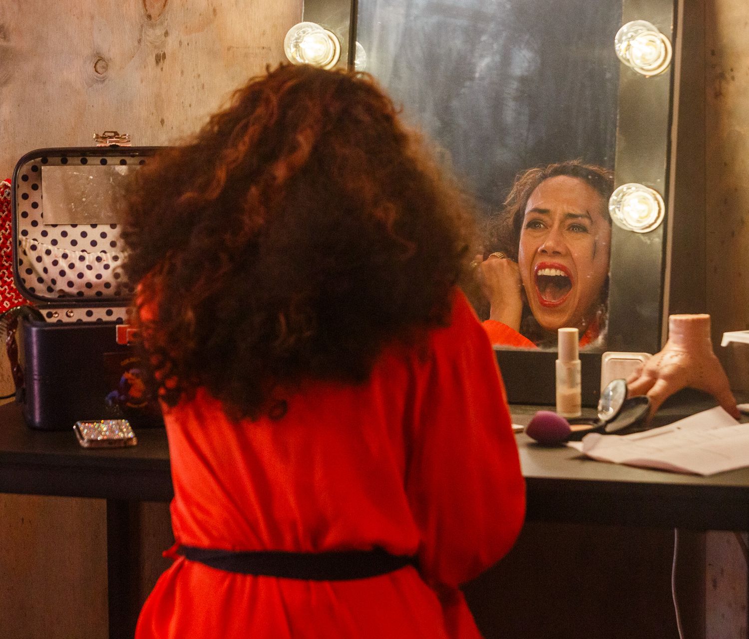 Dramatic close-up shots in theatrical lighting with red tones.
