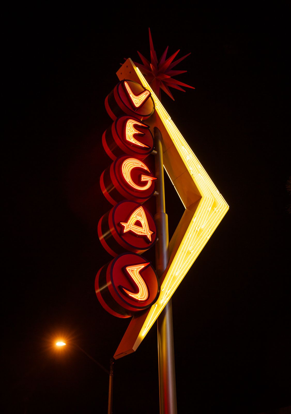 Illuminated vintage neon sign with red and yellow geometric shapes glowing at night.