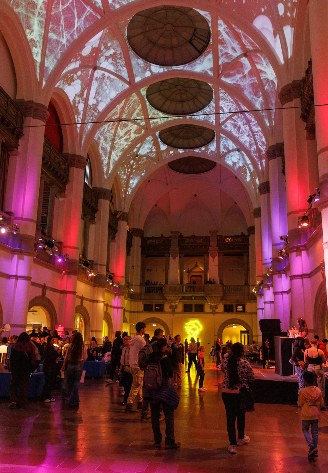 Elegant venue with pink-lit vaulted ceilings and arches filled with event attendees.