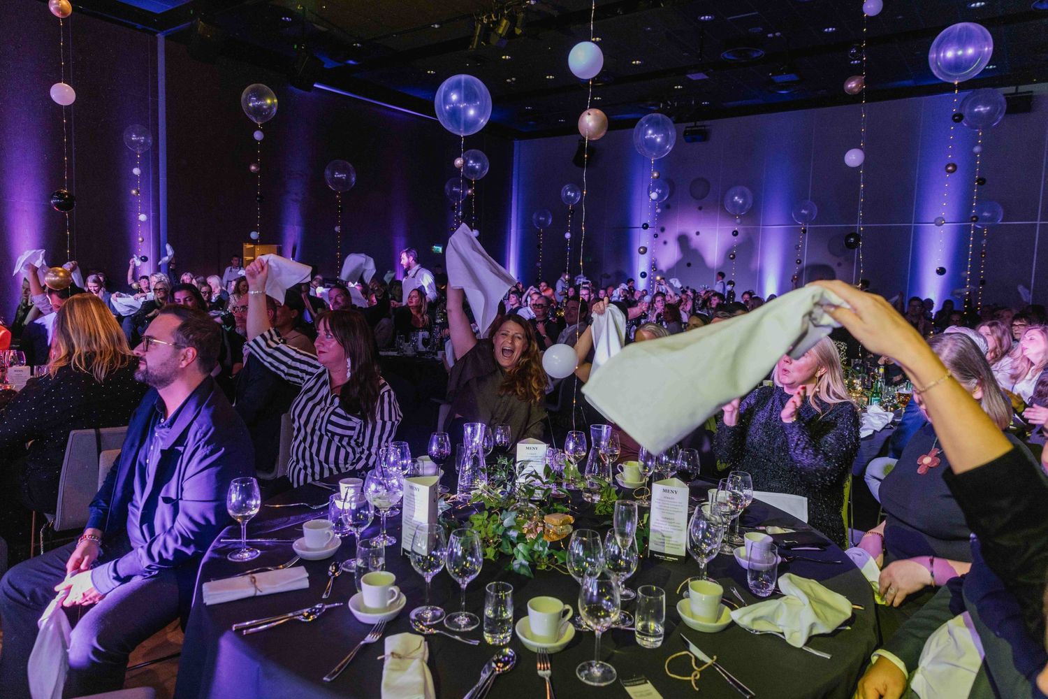 Large event space with purple mood lighting and decorated dining tables.