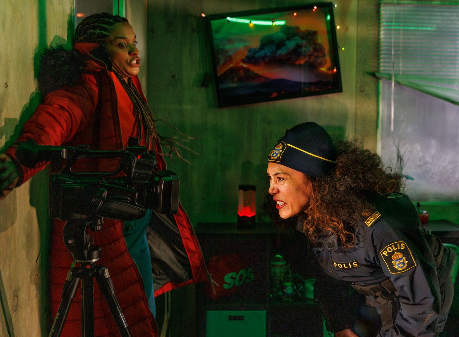 Scene with green lighting shows people in uniform moving through atmospheric space.