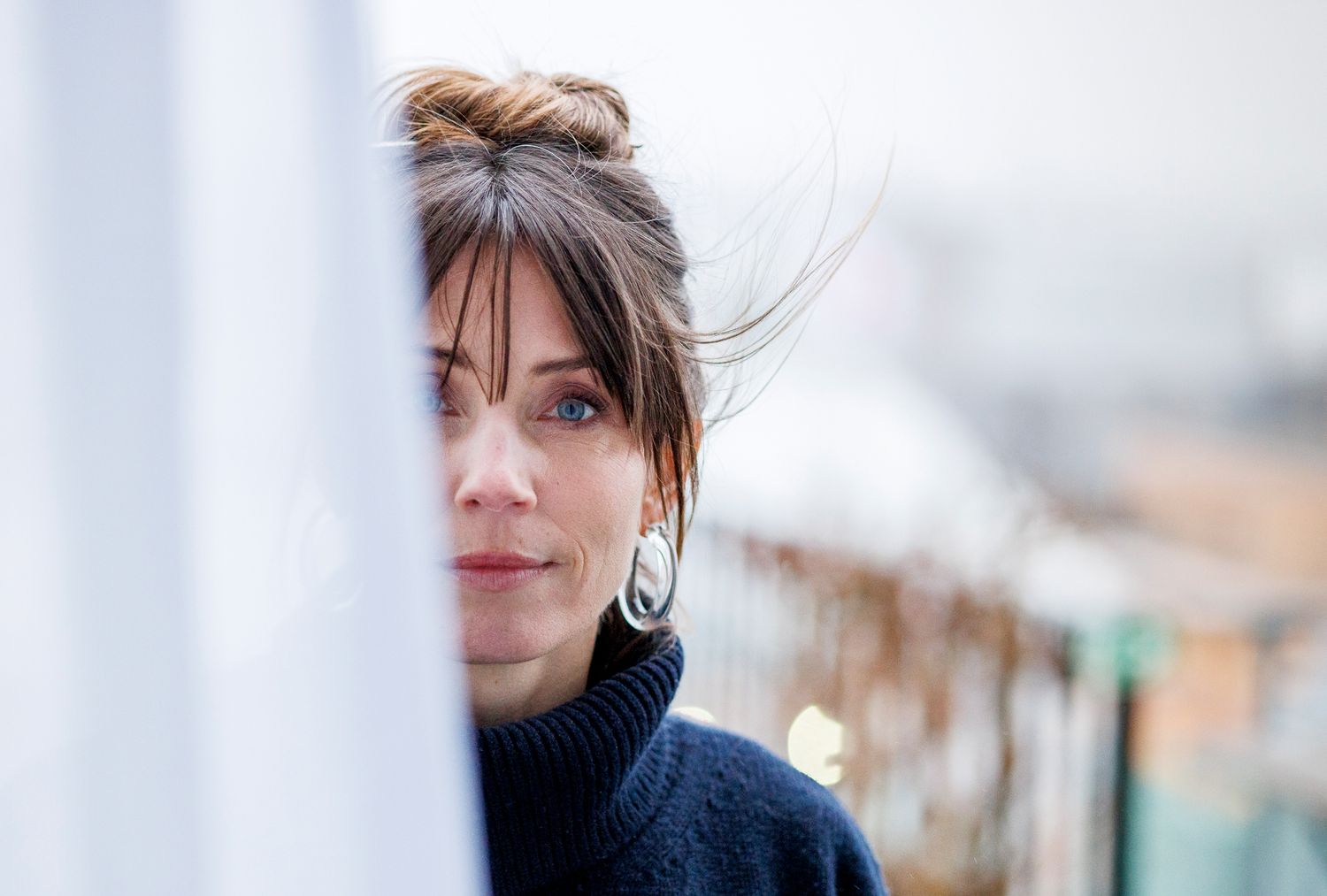 A close-up portrait shot of someone wearing a black turtleneck sweater looking to the side.