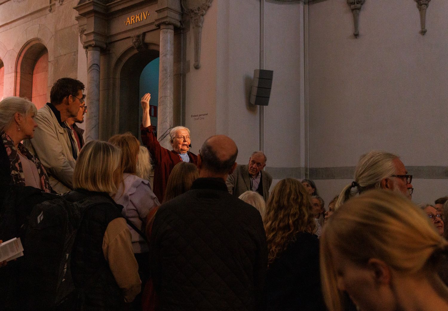 Crowd gathered inside a historic building with ornate architectural details.
