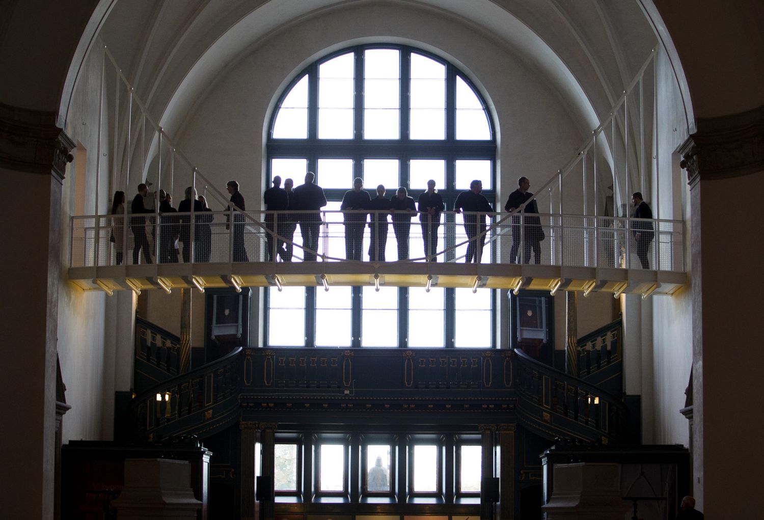 Architectural detail showing arched windows and balcony in a historic building interior.