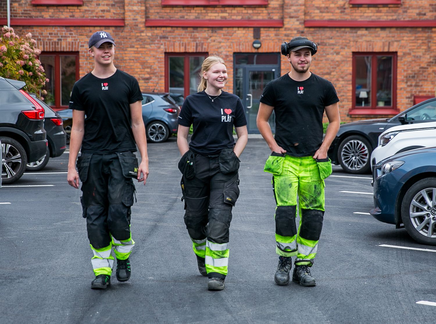 Group of workers in black uniforms with reflective safety pants walking outside.