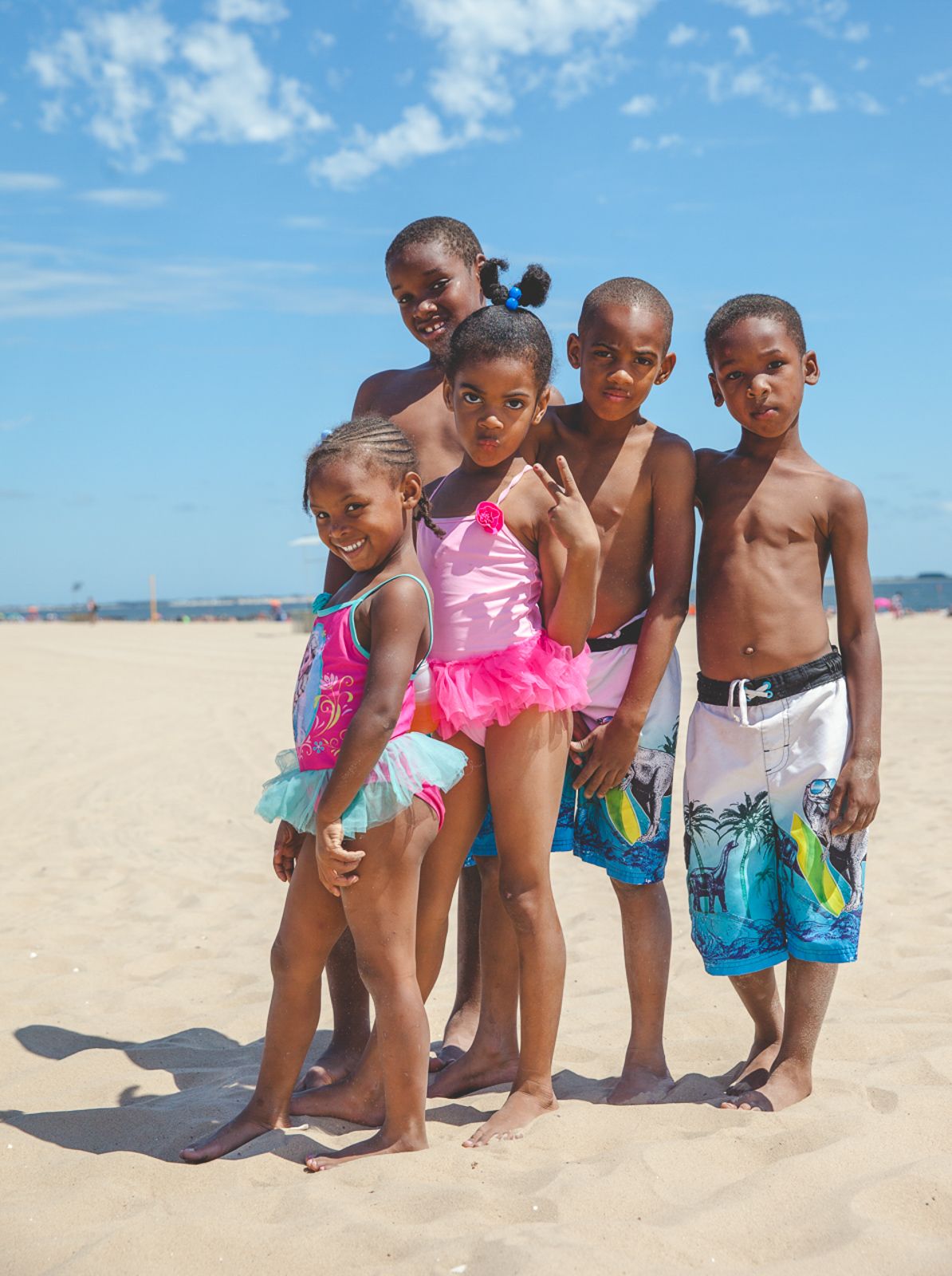 Children in swimsuits play together on a sunny beach, creating joyful moments in the sand.