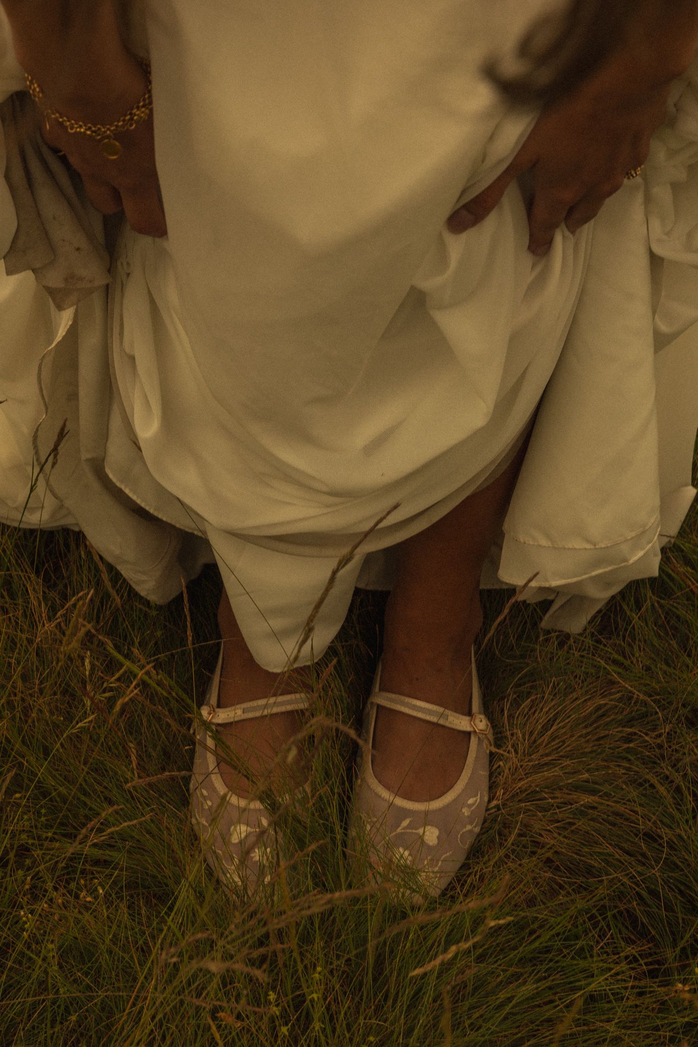Detail shot of the bride's shoes in the green field of Castelluccio di Norcia, Italy