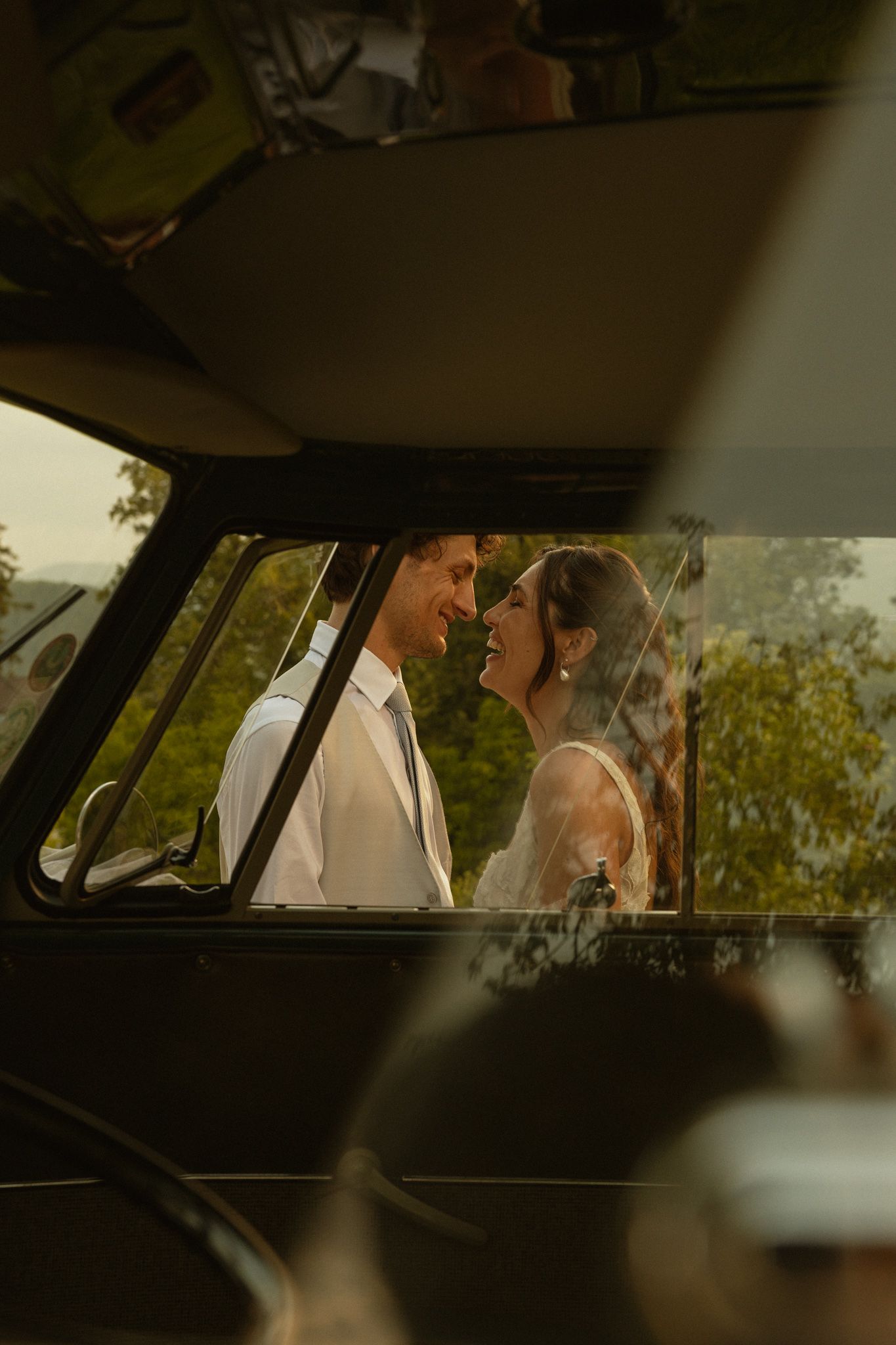 Newlyweds framed through the minivan window at golden hour, Dolomites