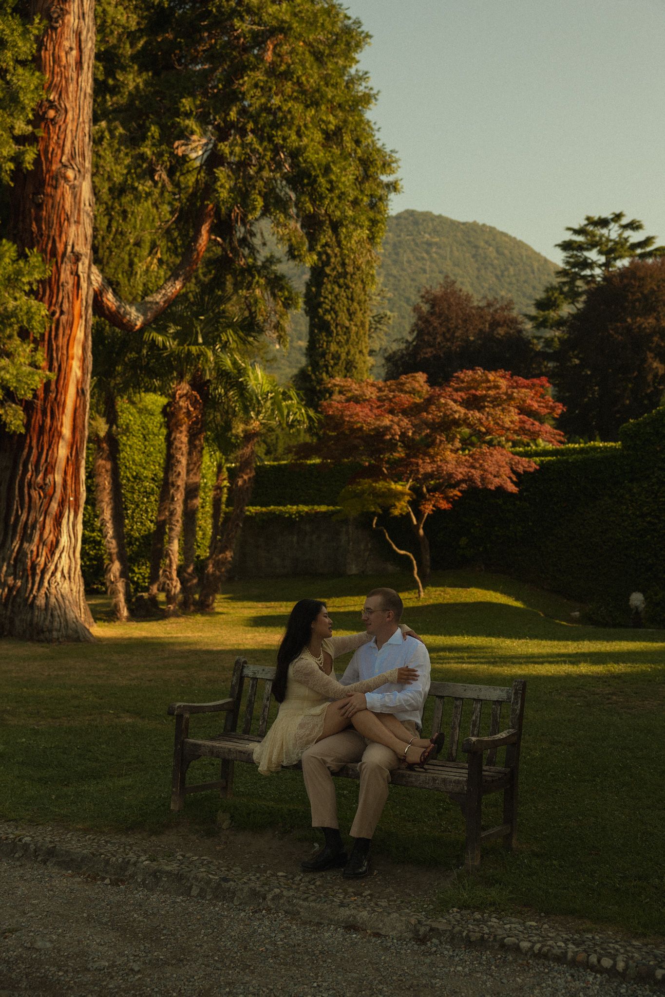 Couple embracing on a bench under a tree, in a park, Lake Como