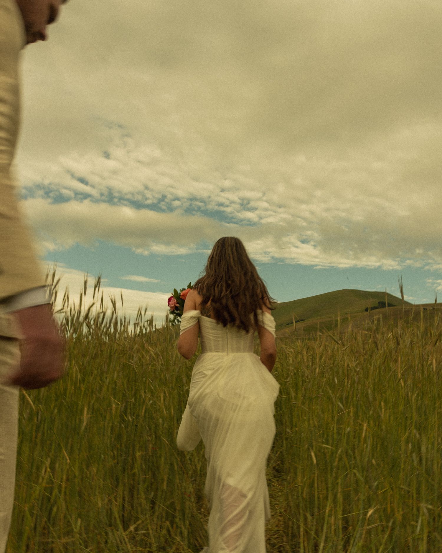Bride and groom walking through the blooming plain of Castelluccio di Norcia