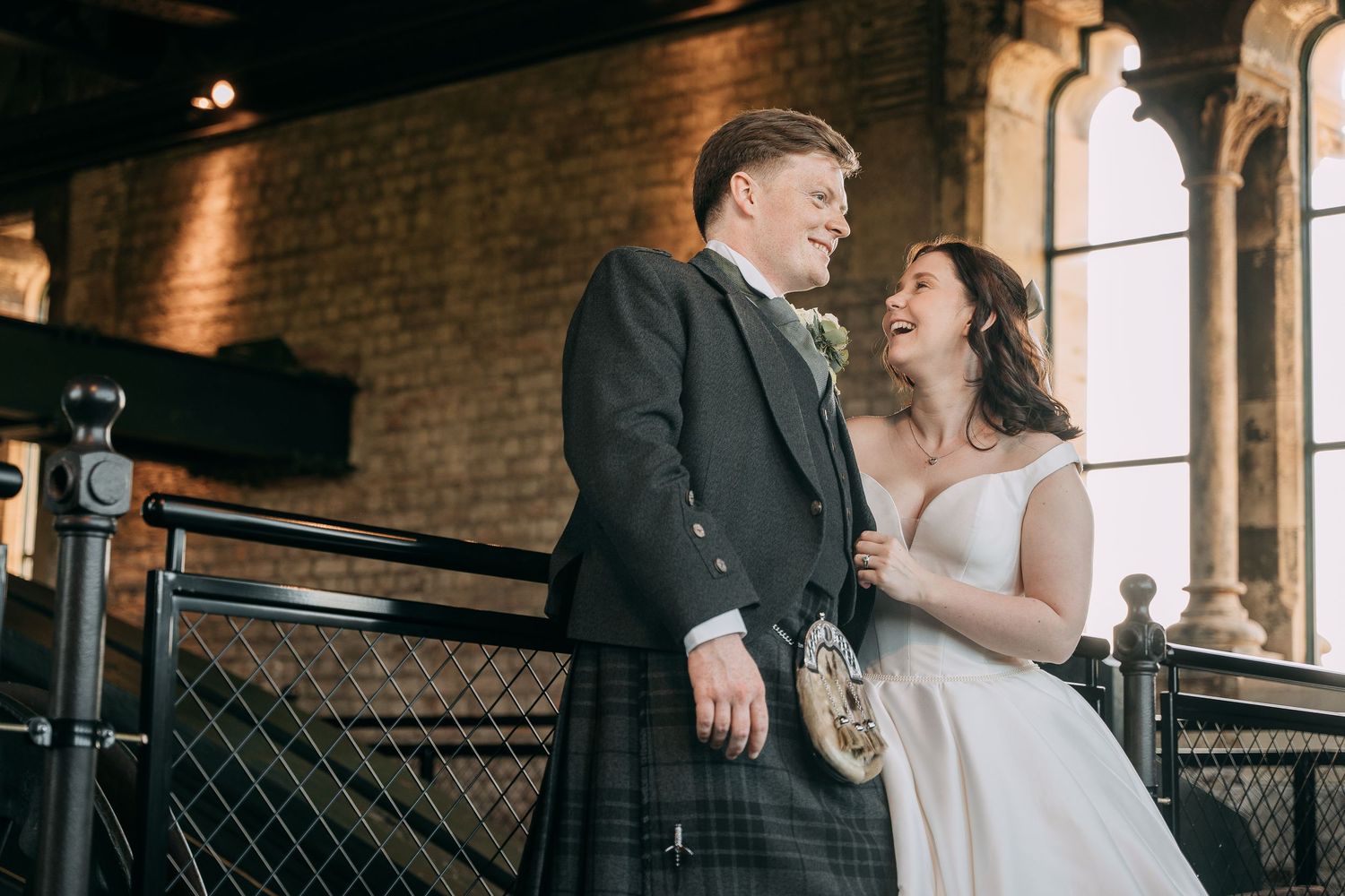 Bride laughs with Groom while holding onto him