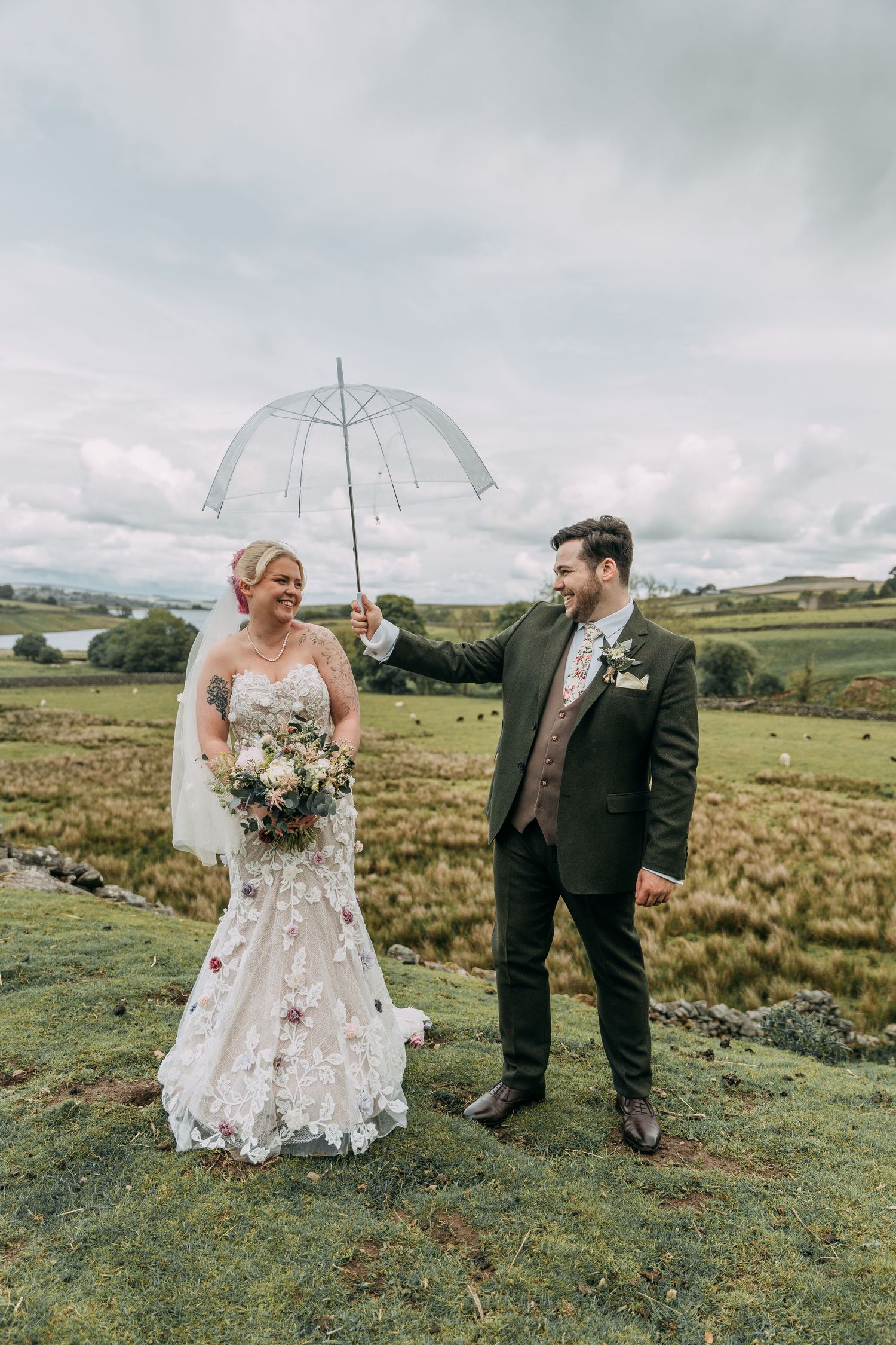 Groom jokingly holds umbrella over Bride, as they both laugh