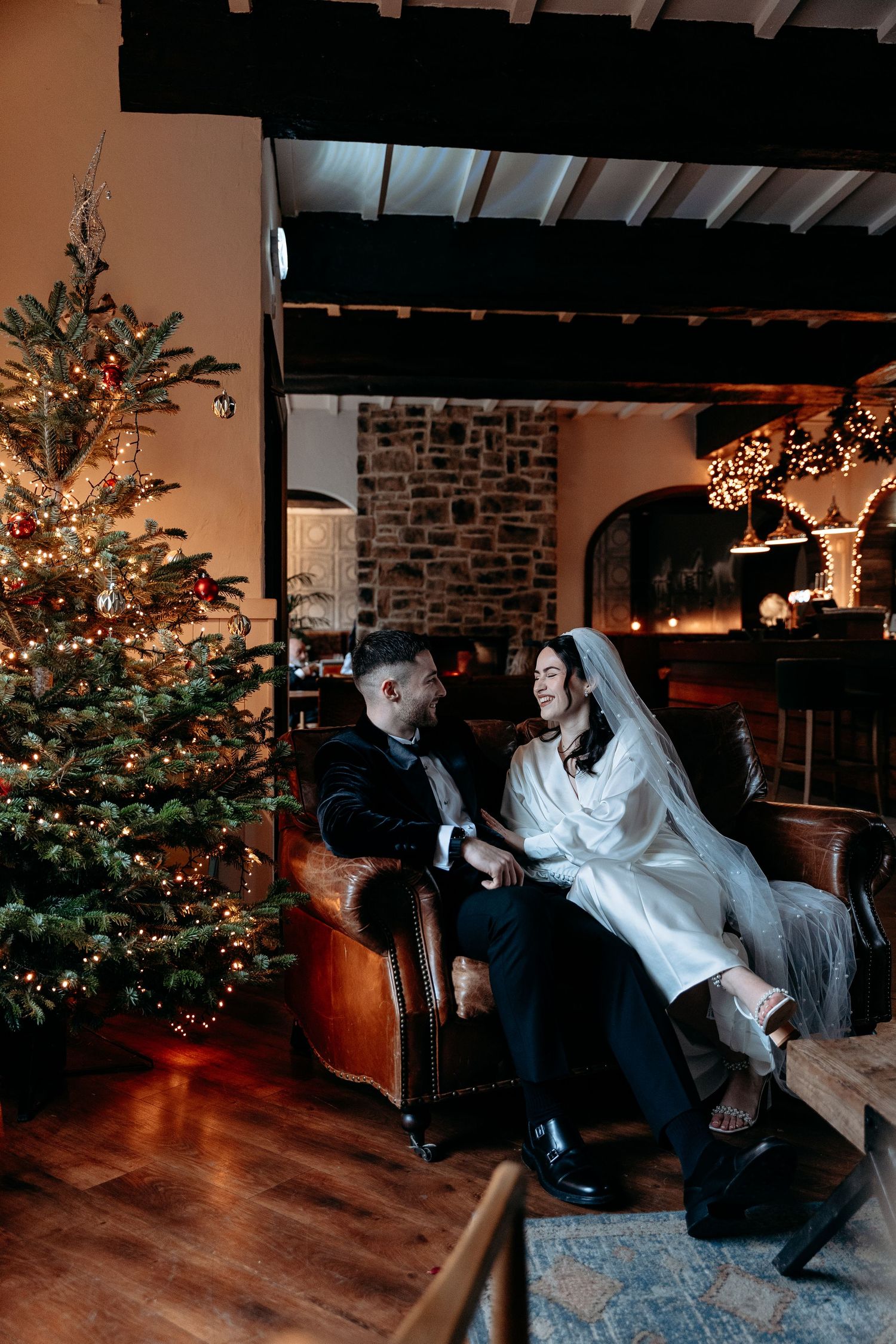 Bride and Groom sit next to a Christmas tree in a warm room, as they chat about their day at The Croft Hotel