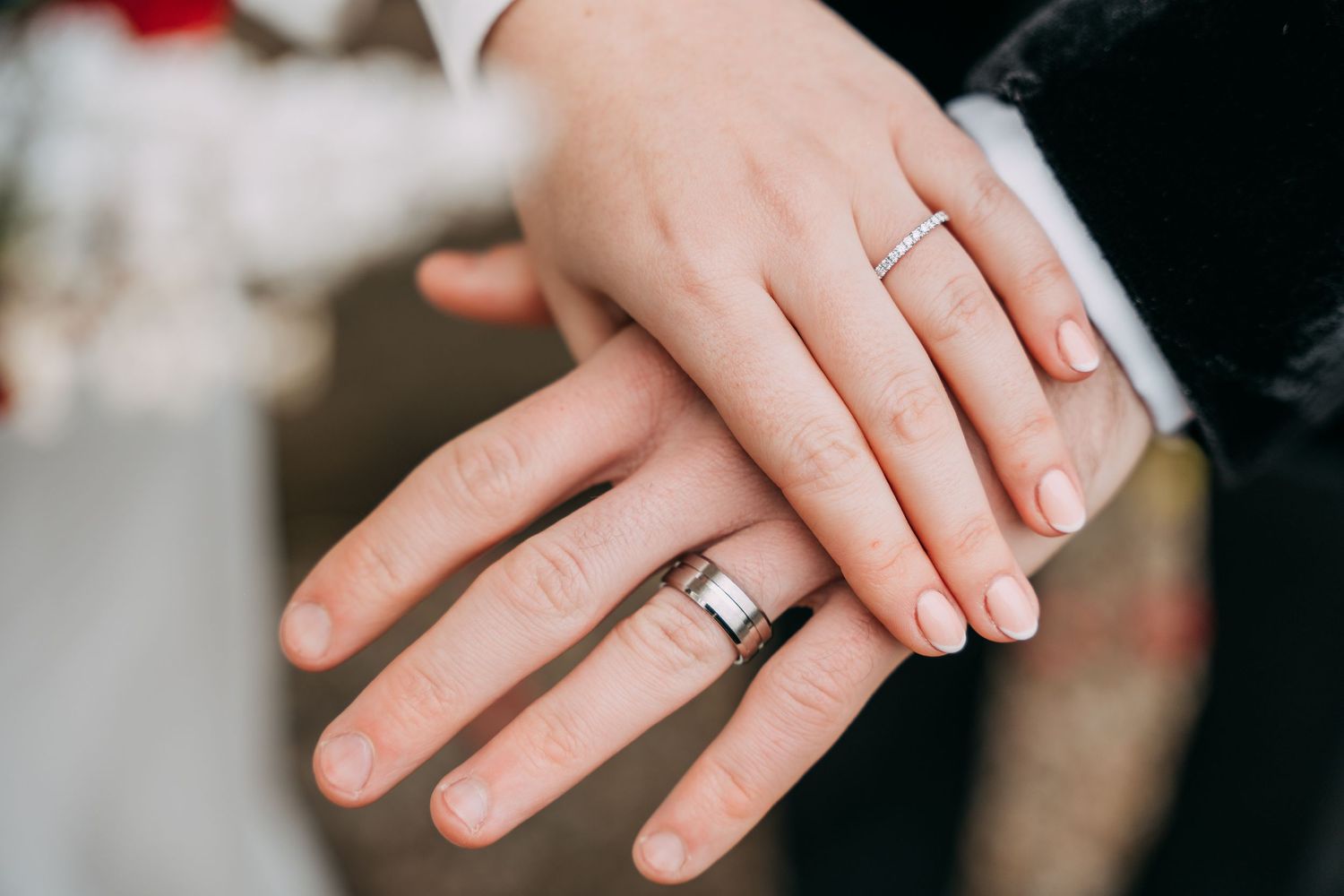 Couple with hands on top of one another, showing off their new rings