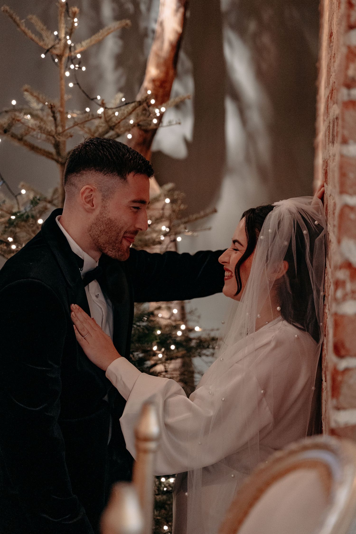 Bride leans against wall with hand on Groom with laughter, while the Groom leans over her at The Croft Hotel