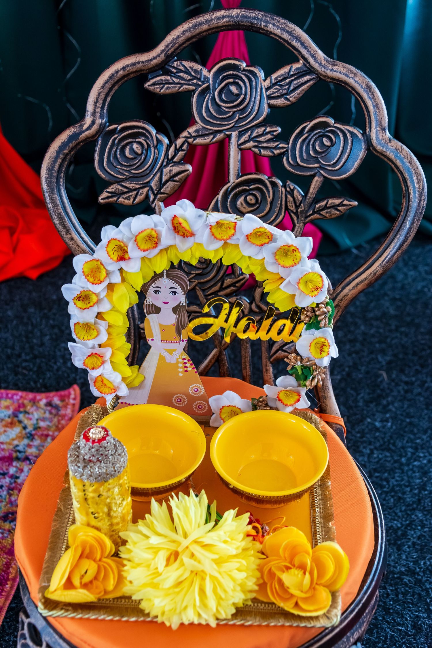 Traditional Indian Haldi ceremony tray with flowers, turmeric bowls, and decorative bride figurine.