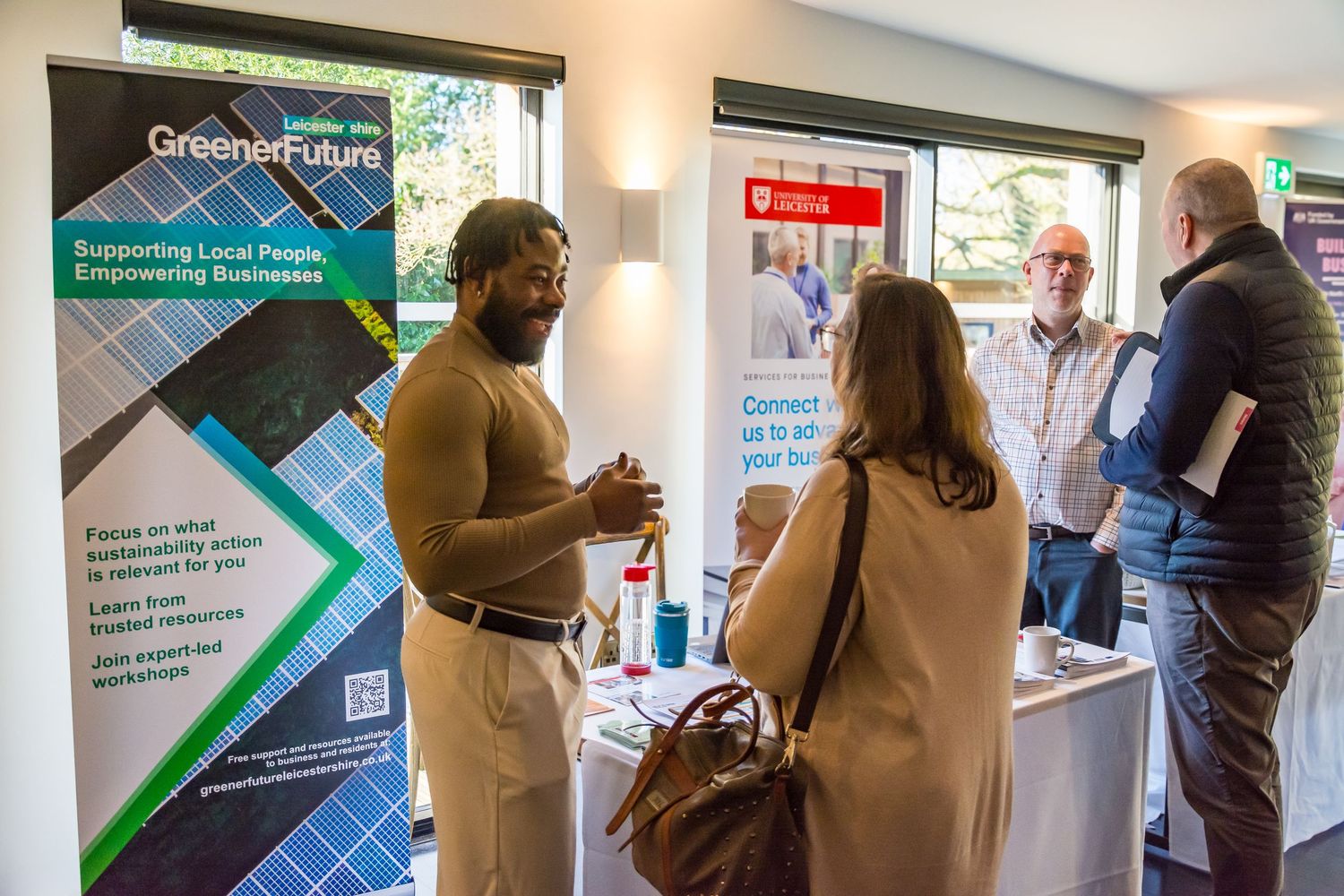 People networking at a Greener Future business event with promotional banners in background.