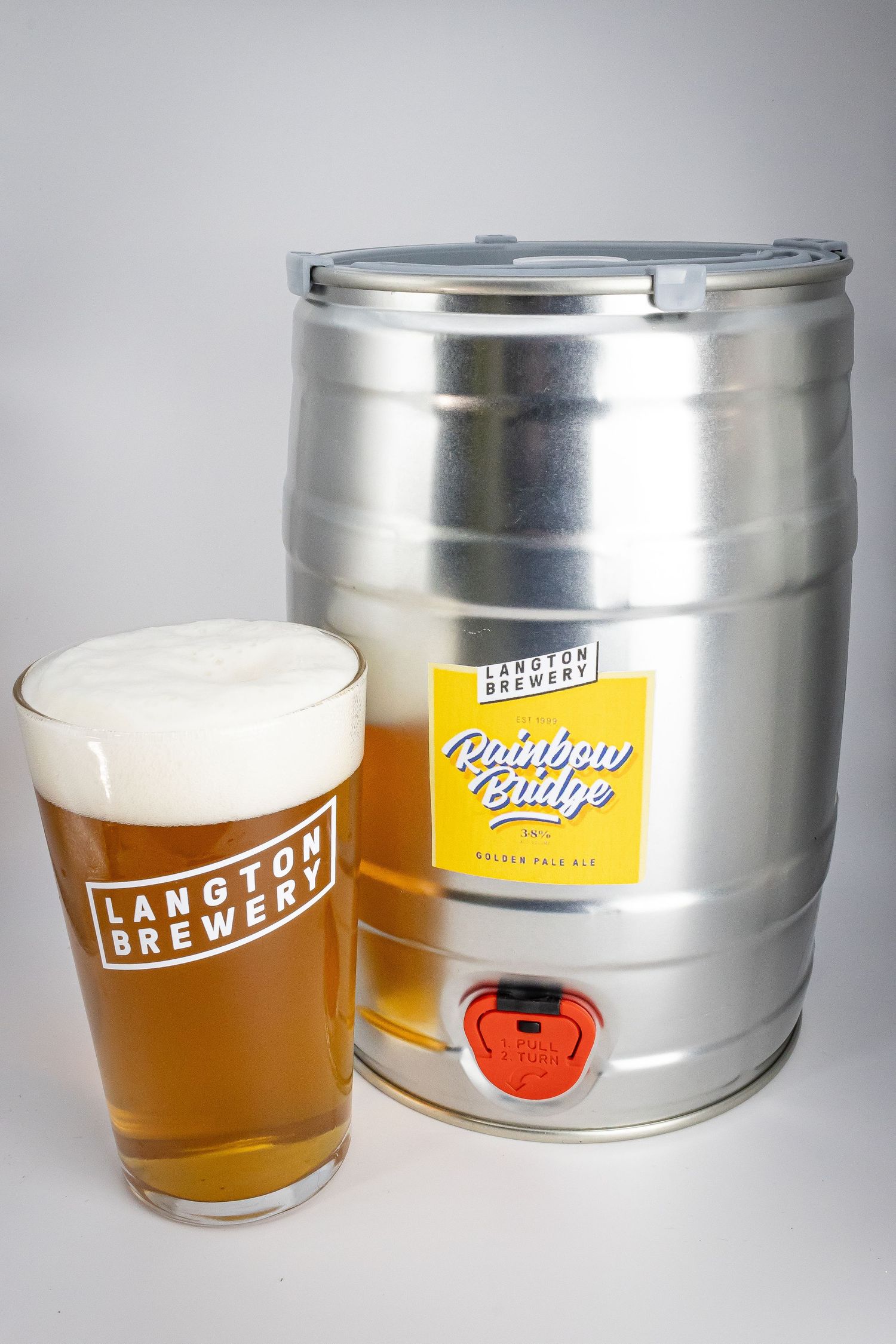 Langton Brewery Rainbow Bridge Golden Pale Ale in a pint glass beside a mini stainless steel keg on white background.