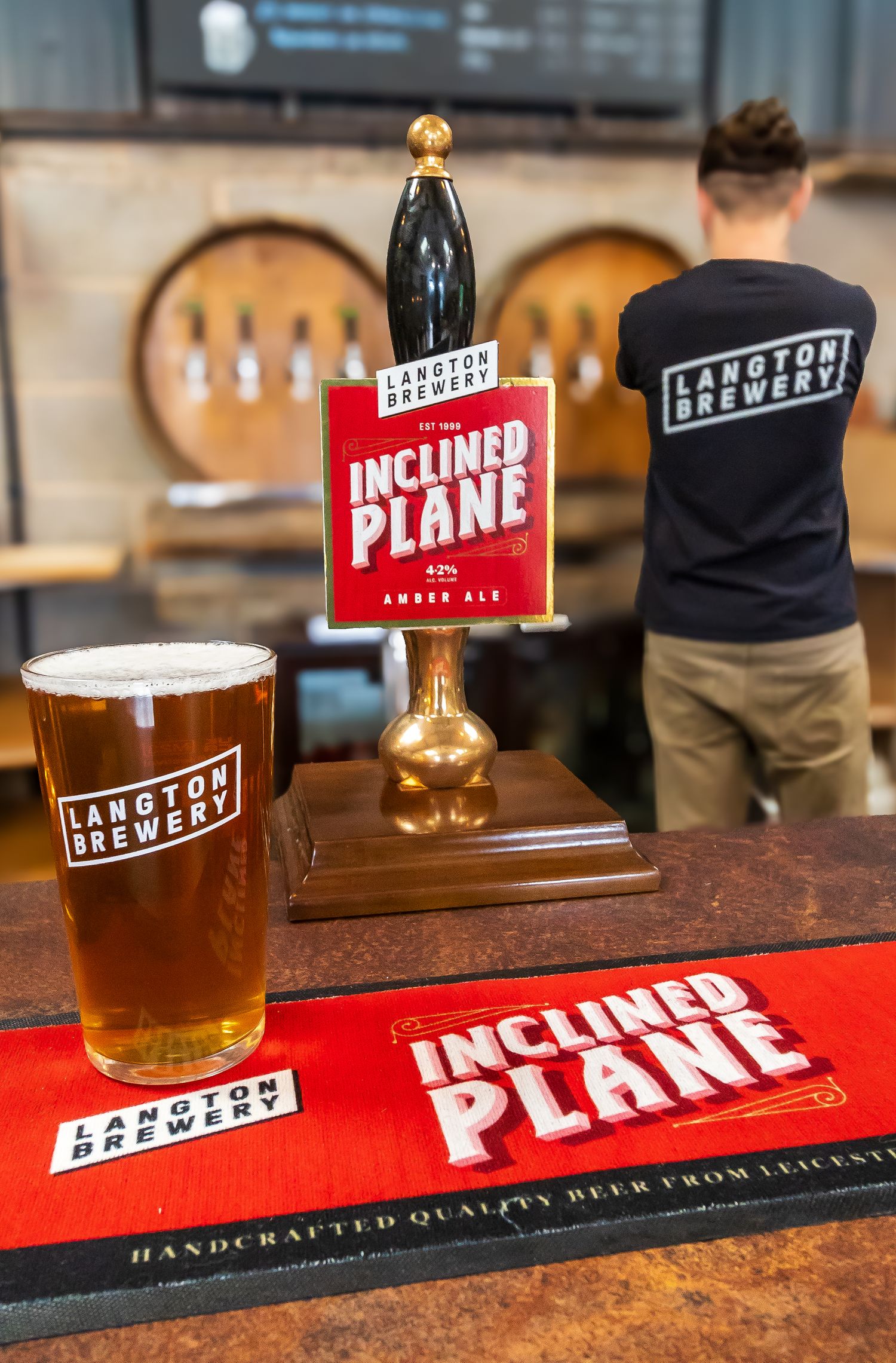 Pint of Langton Brewery Inclined Plane amber ale on bar counter with branded pump clip and bar mat.