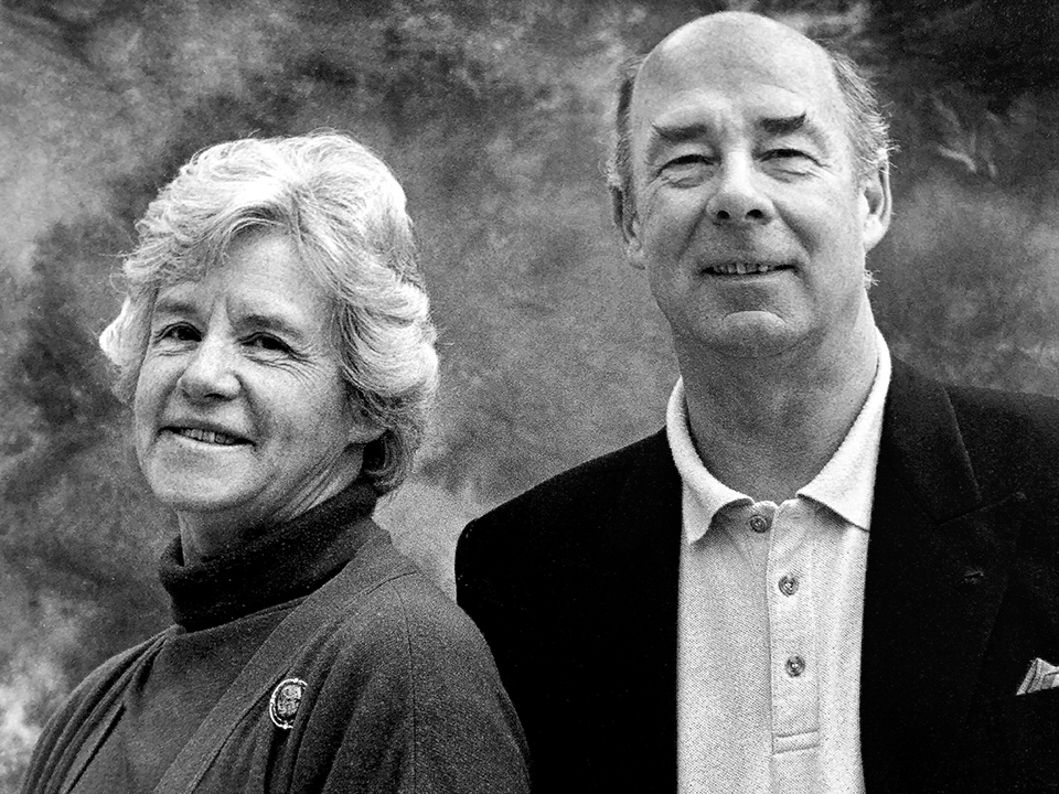 A black and white portrait photograph of a smiling older man and woman. Photo restoration, bringing back details to worn photograph.