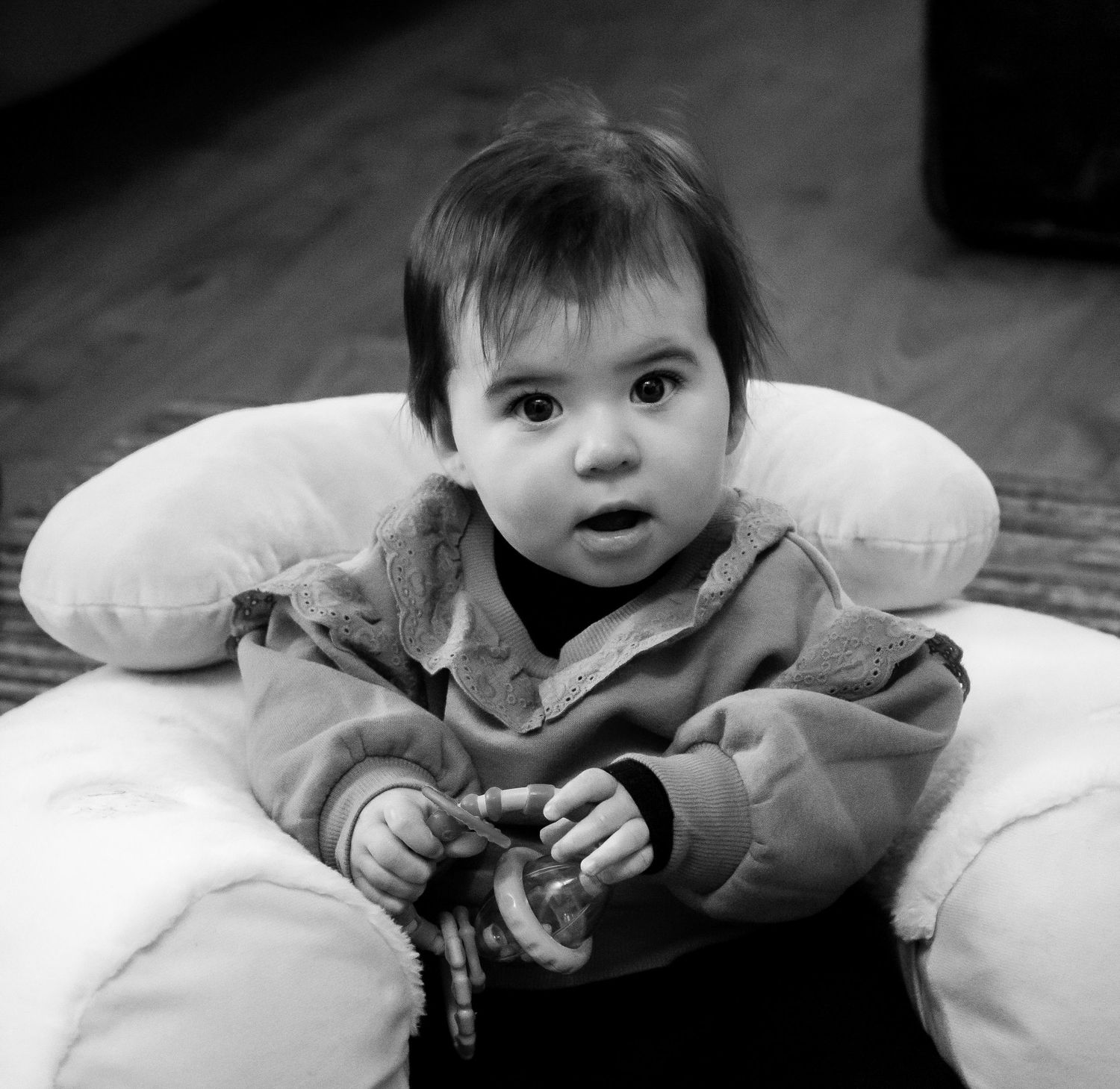 A curious baby sits in a nursing pillow in this classic black and white portrait photo.