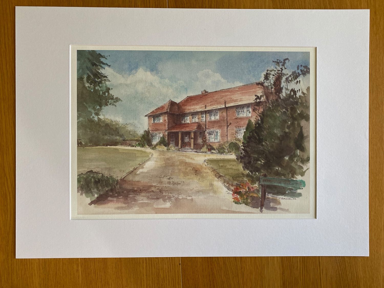 Watercolor painting of a red brick country manor house with driveway and surrounding trees.