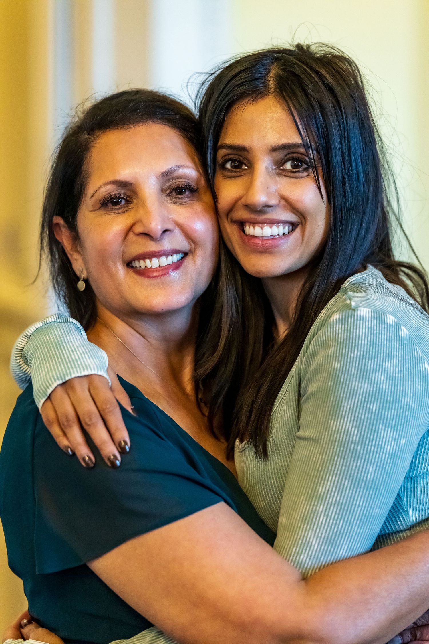 Two smiling women embracing warmly while posing together for a photo.
