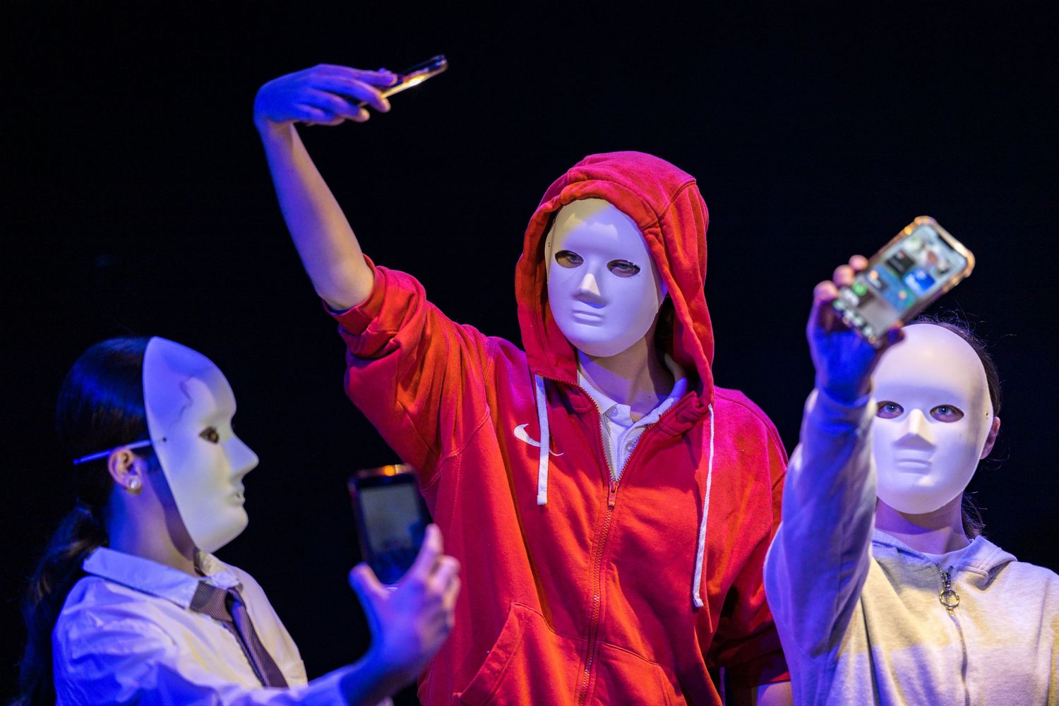 Three masked performers in a dramatic school theatre production.