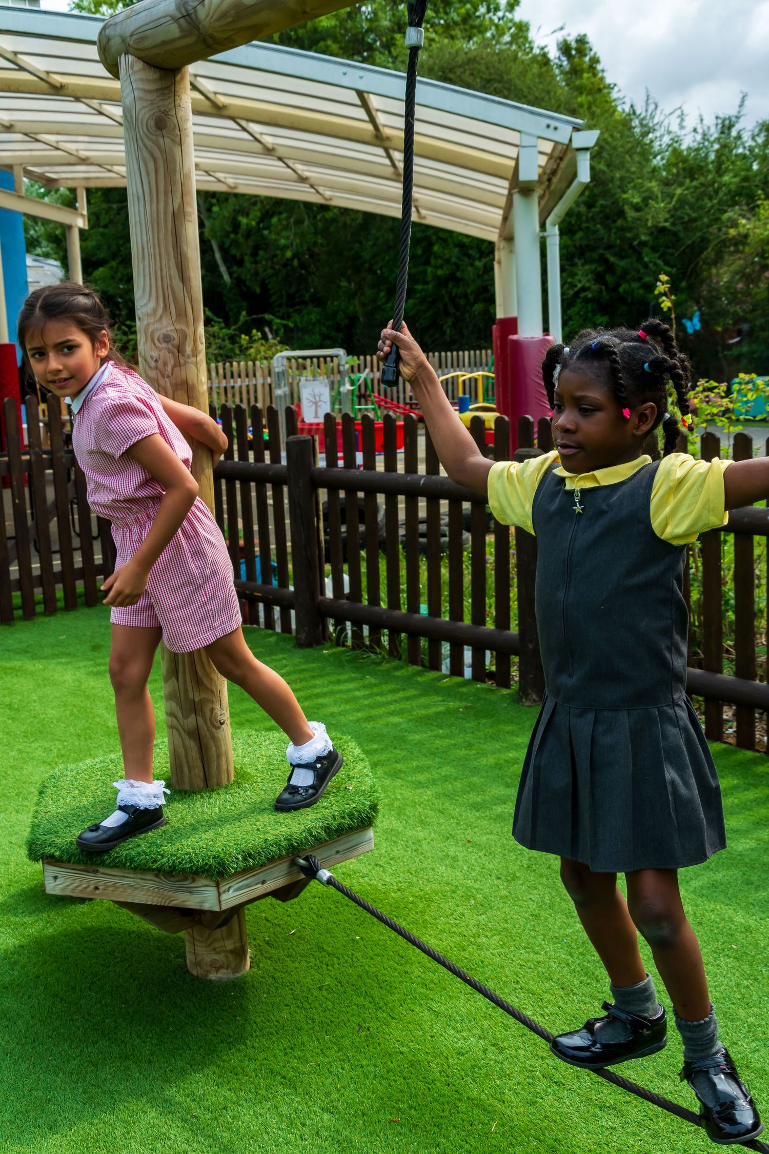 Two young girls playing on an outdoor playground equipment. LJPhotostop capturing precious moments.