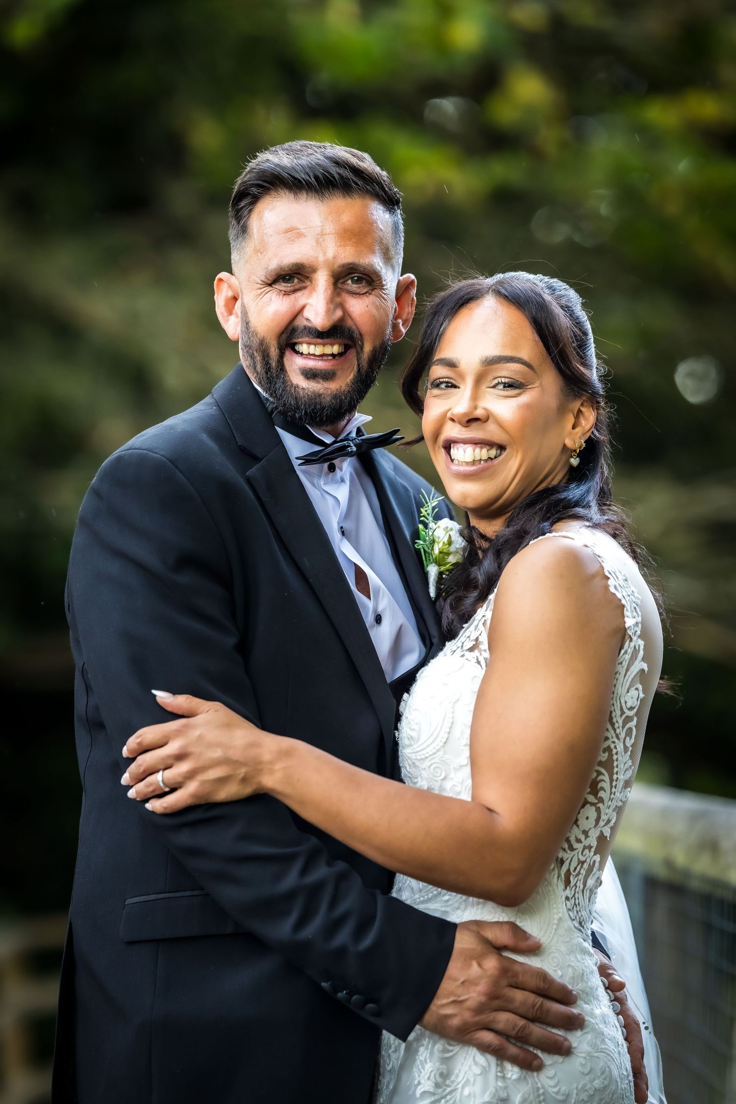 Happy bride and groom embracing outdoors on wedding day, smiling couple in formal attire.
