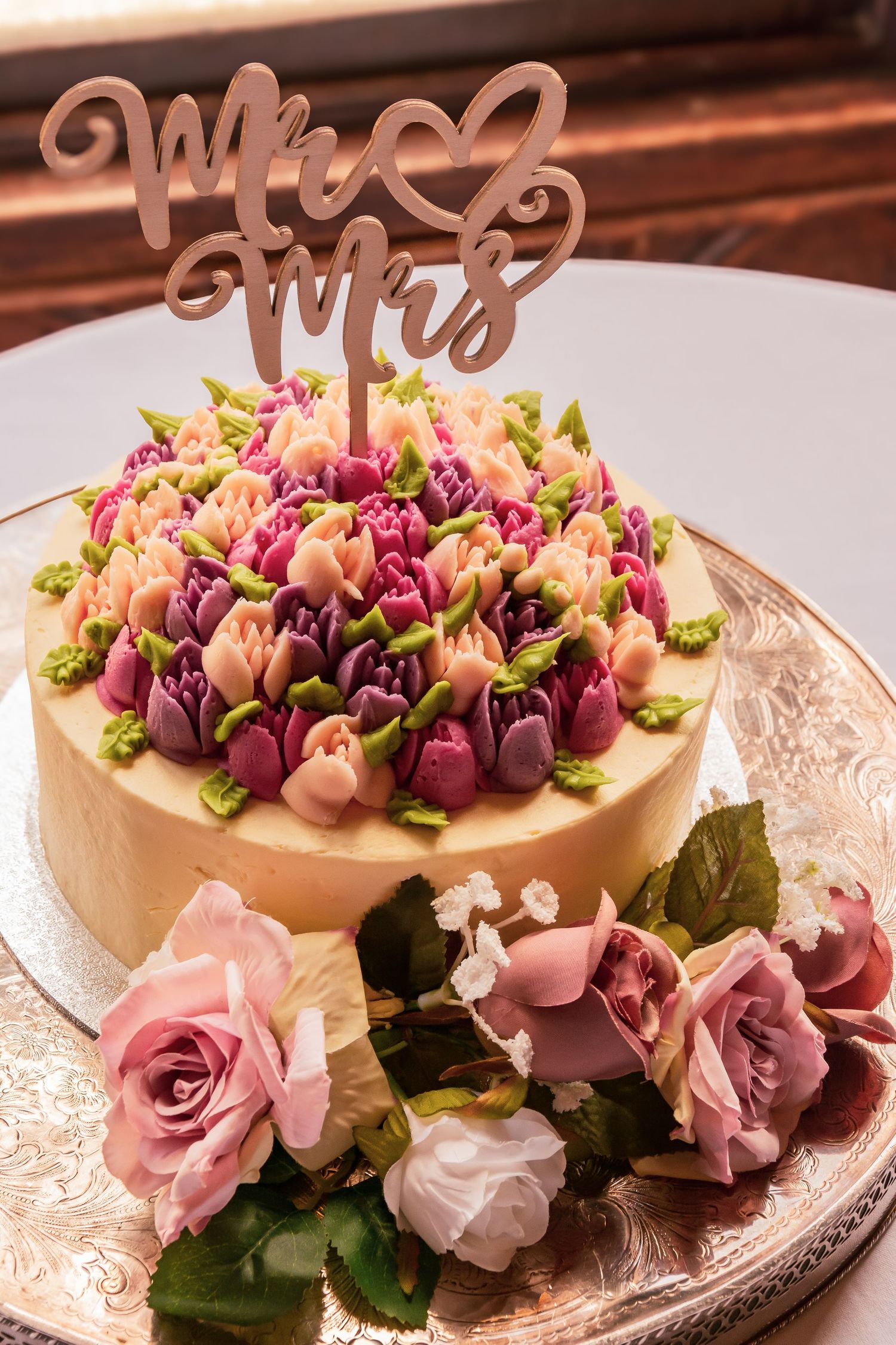 Elegant wedding cake decorated with colorful buttercream tulips and topped with a Mr and Mrs cake topper.